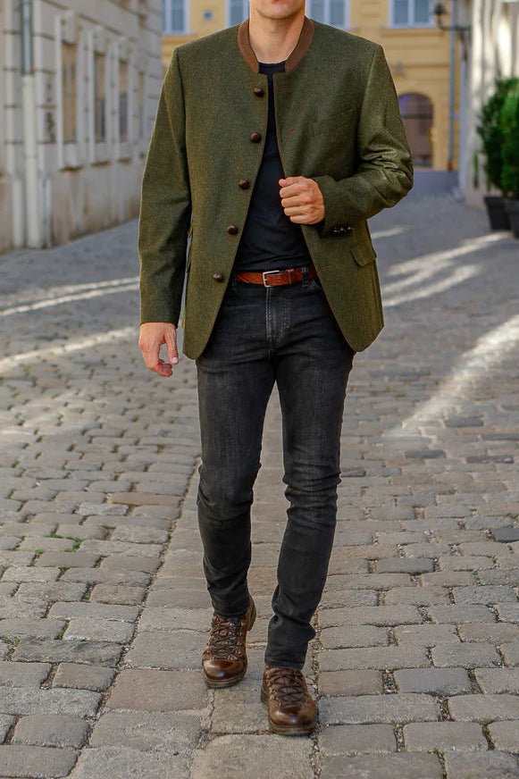 Man walking down a cobblestone street wearing a green jacket and dark jeans.