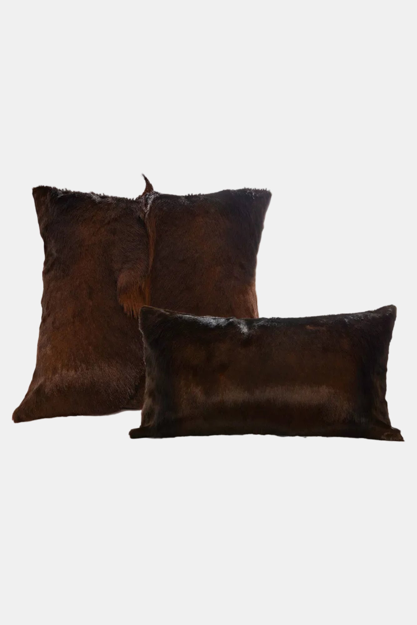 Two brown cowhide pillows on a white background