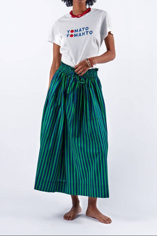 Woman wearing a white t-shirt with text and a green striped skirt on a white background