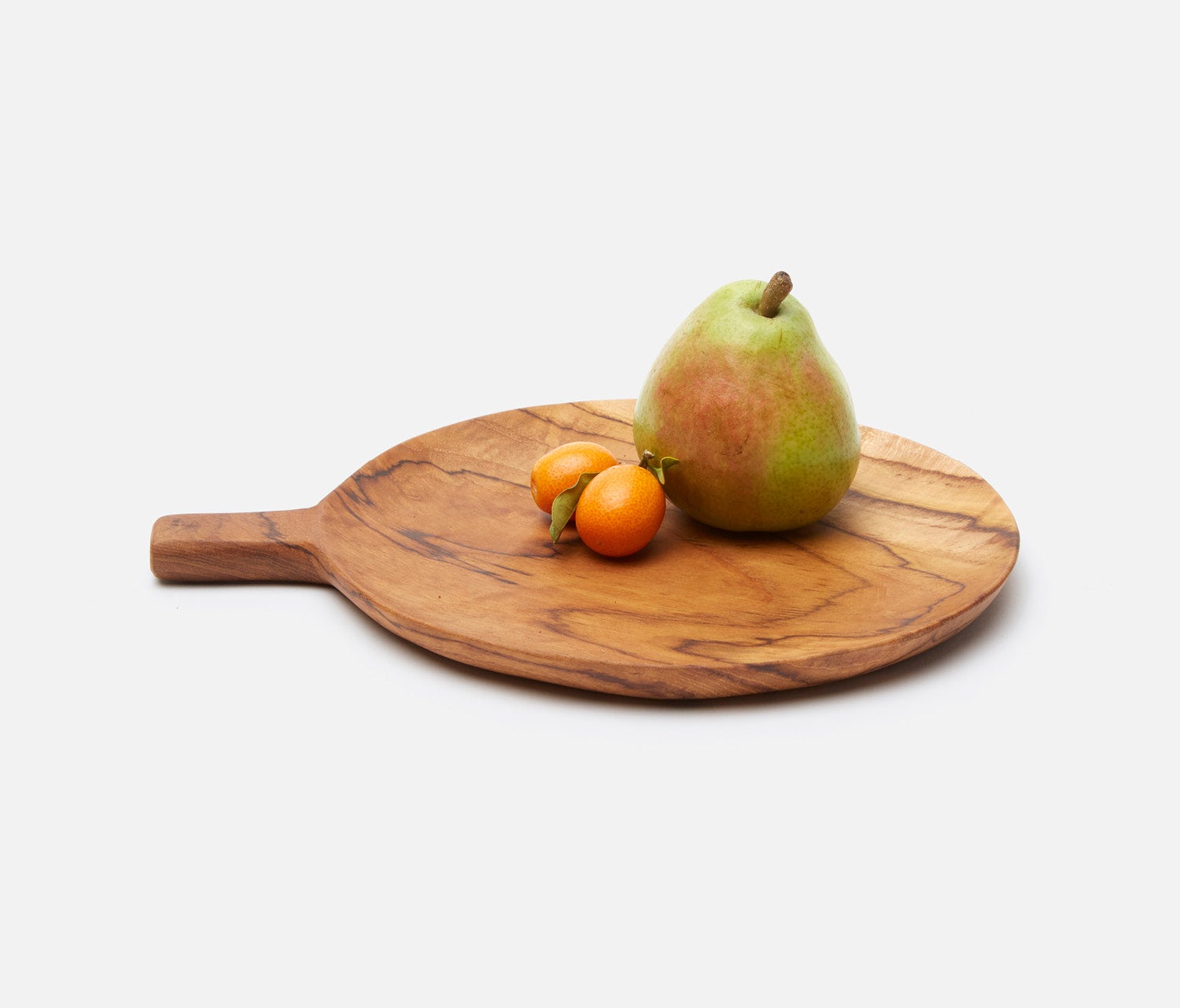 A round wooden serving board with a handle, styled with a green pear and two small orange fruits, on a light gray background.