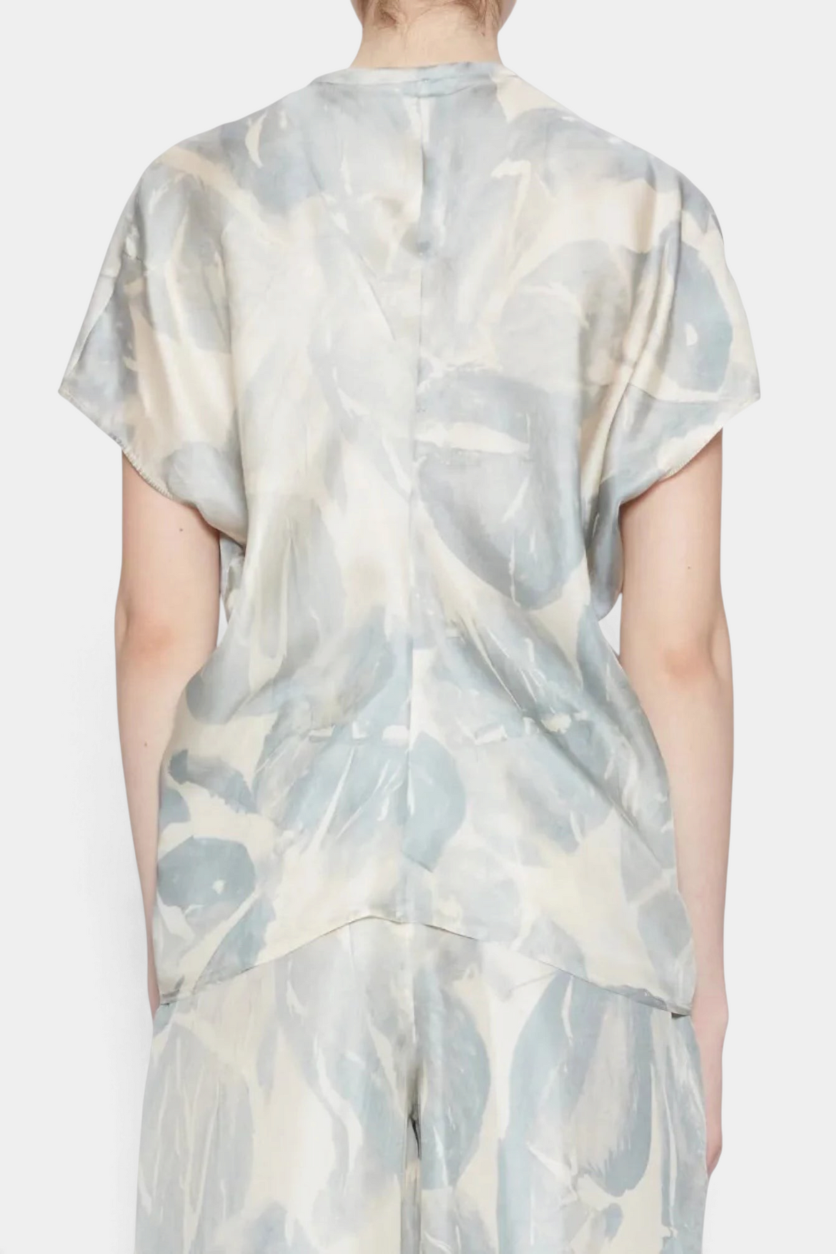 Person wearing a light-colored outfit with abstract pattern on a white background