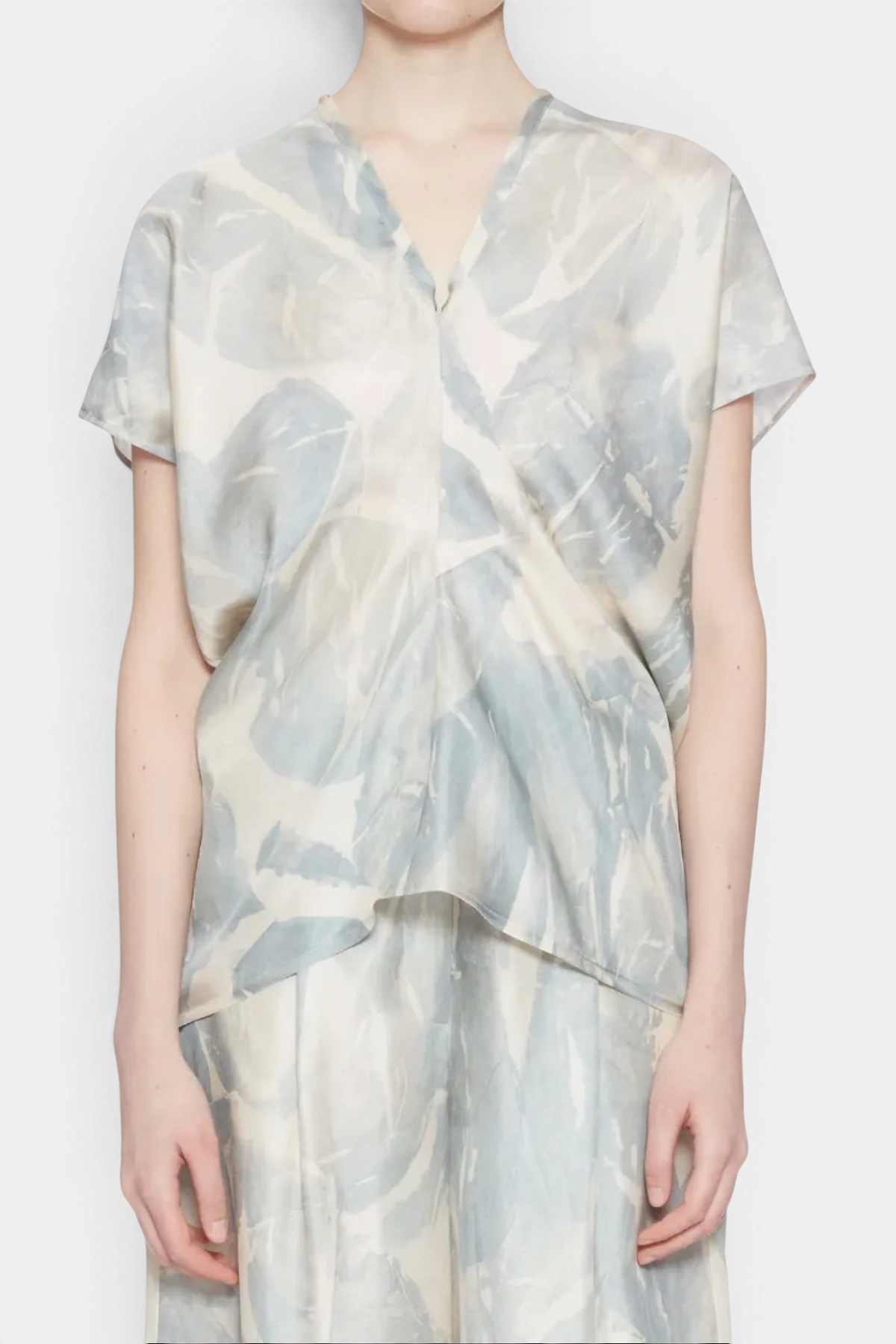 A model wearing a light blue and cream abstract patterned short-sleeve top and matching trousers against a plain white background.