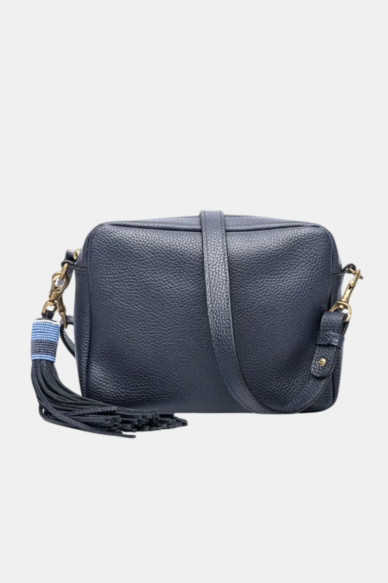 A brown leather handbag with a long shoulder strap, a tassel on the zipper, and a detachable shoulder strap.