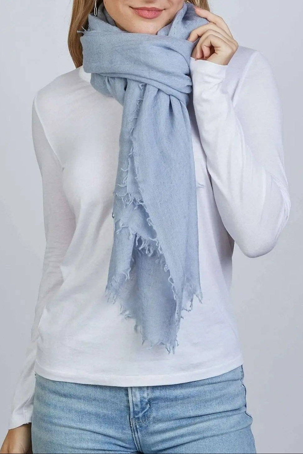 Woman wearing a light blue scarf on a plain background