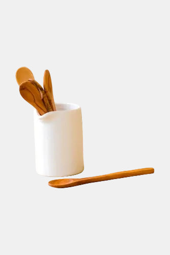 White ceramic container with wooden utensils on a wooden surface
