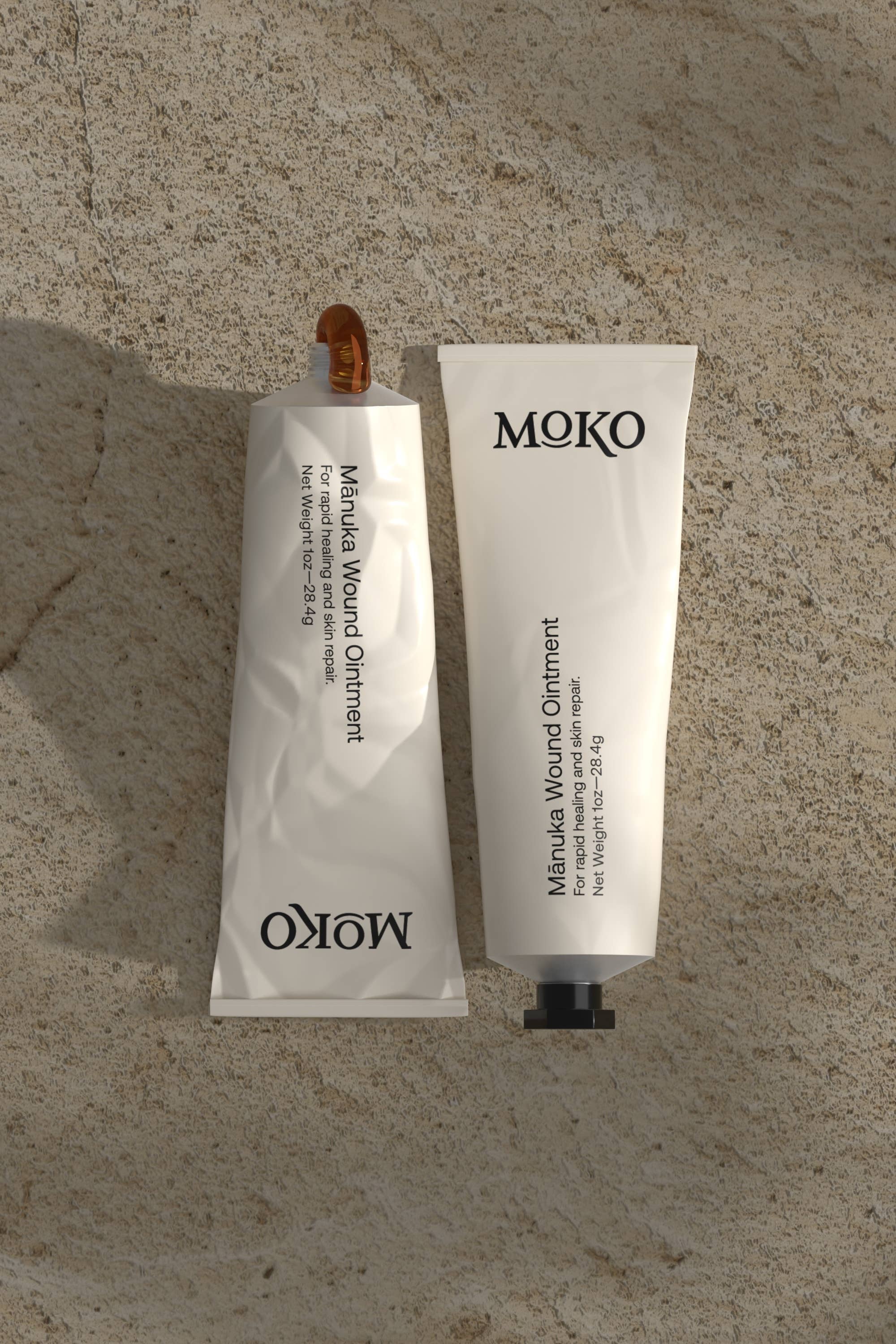 Two tubes of MOKO Manuka Wound Ointment on a textured stone surface