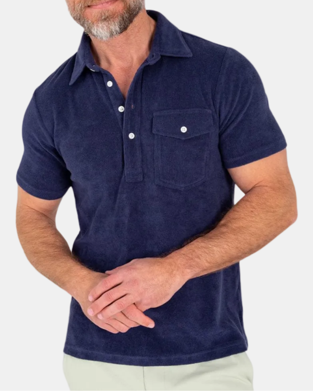 A man wearing a navy blue terrycloth polo shirt with a collar, short sleeves, and a front pocket.