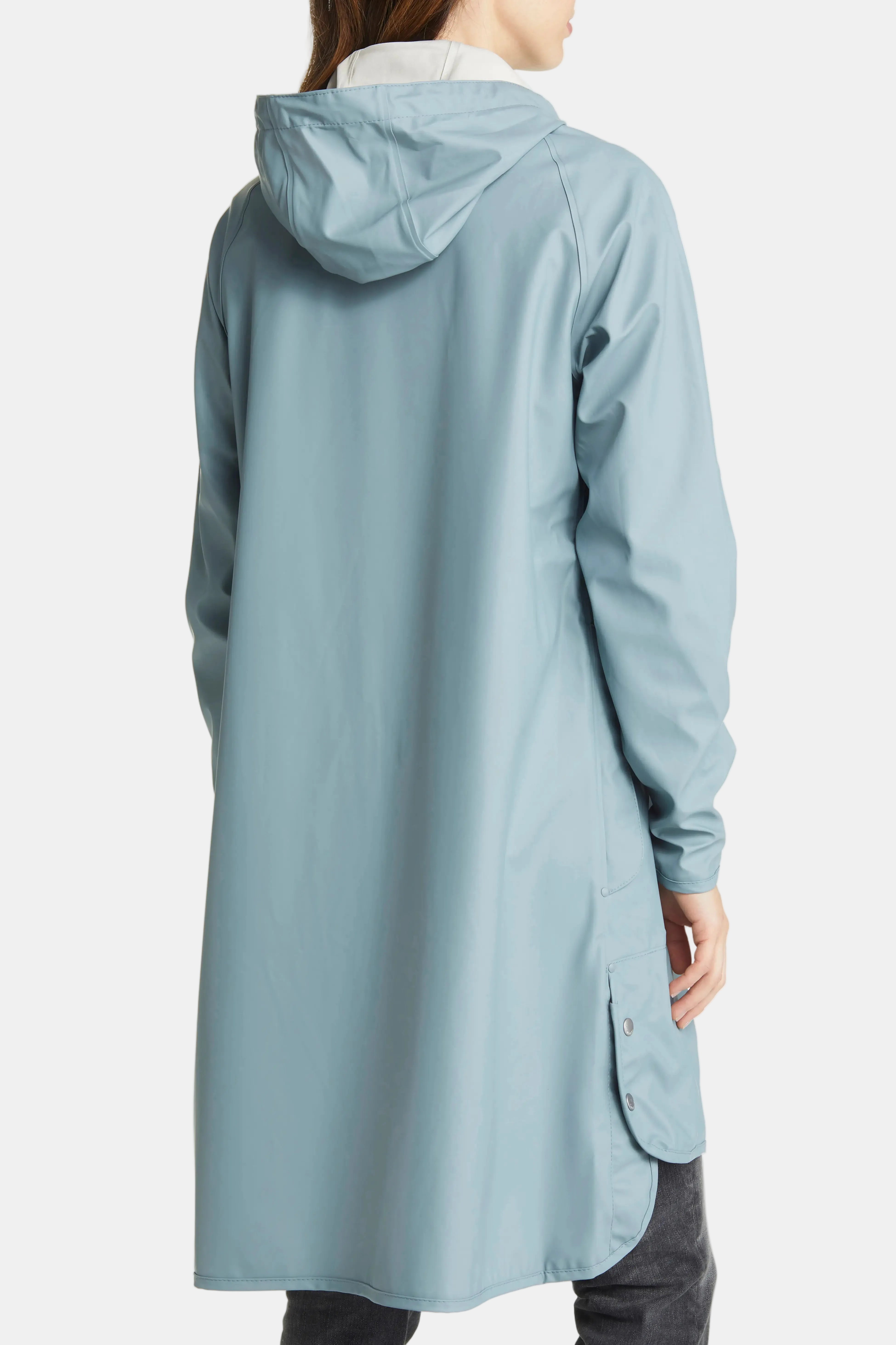 A person shown from the back wearing a light blue hooded raincoat over a white top and dark pants, photographed against a plain white studio background.