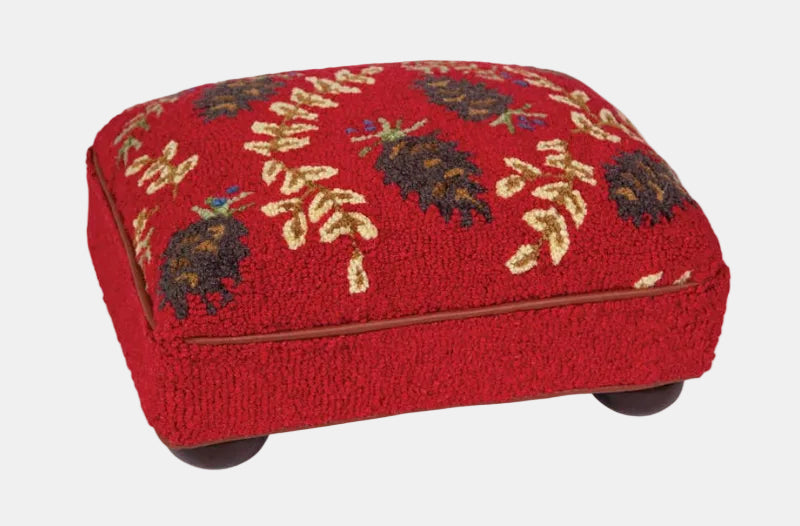 Red ottoman with pine cone and leaf pattern on a white background