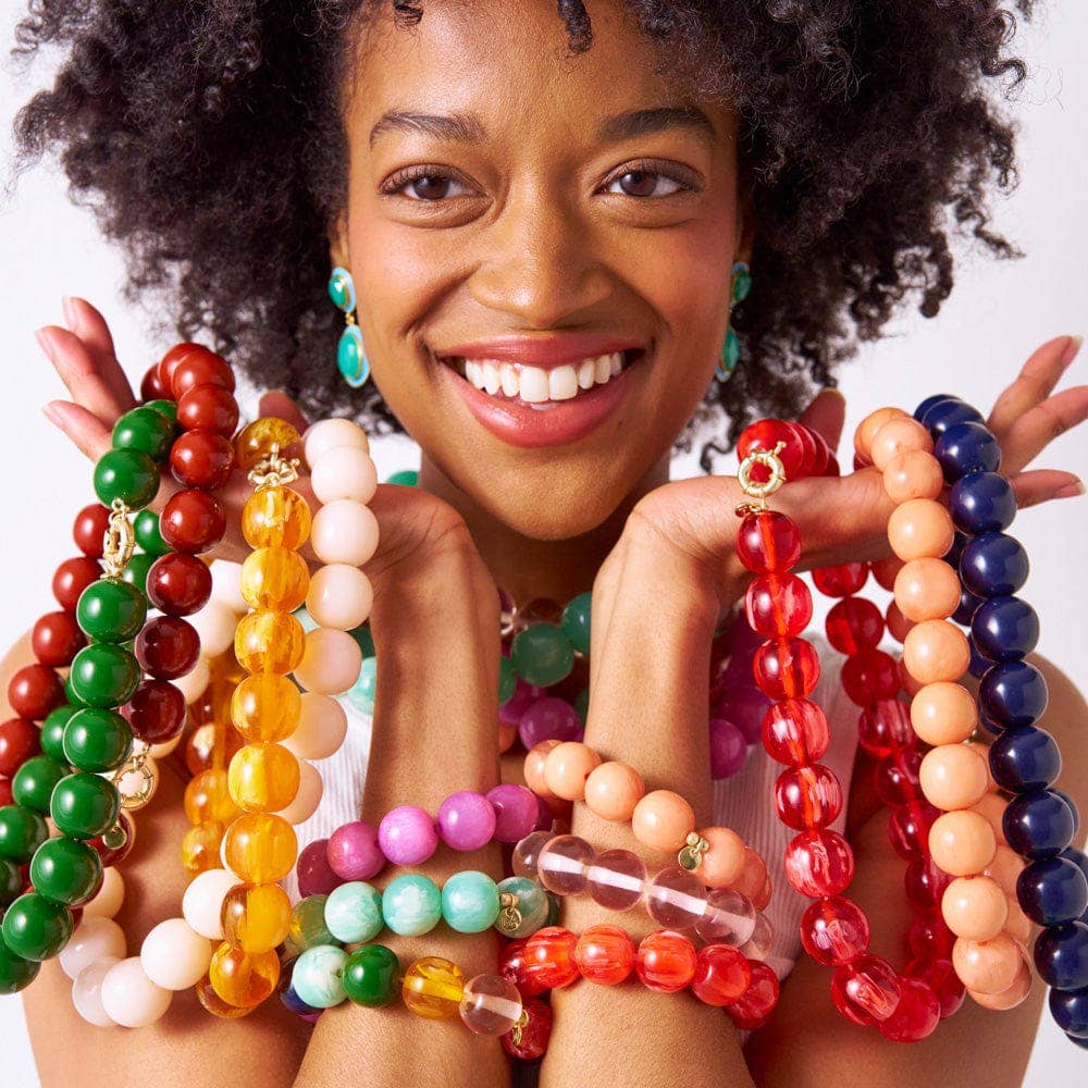 Woman holding and displaying a variety of colorful beaded bracelets.