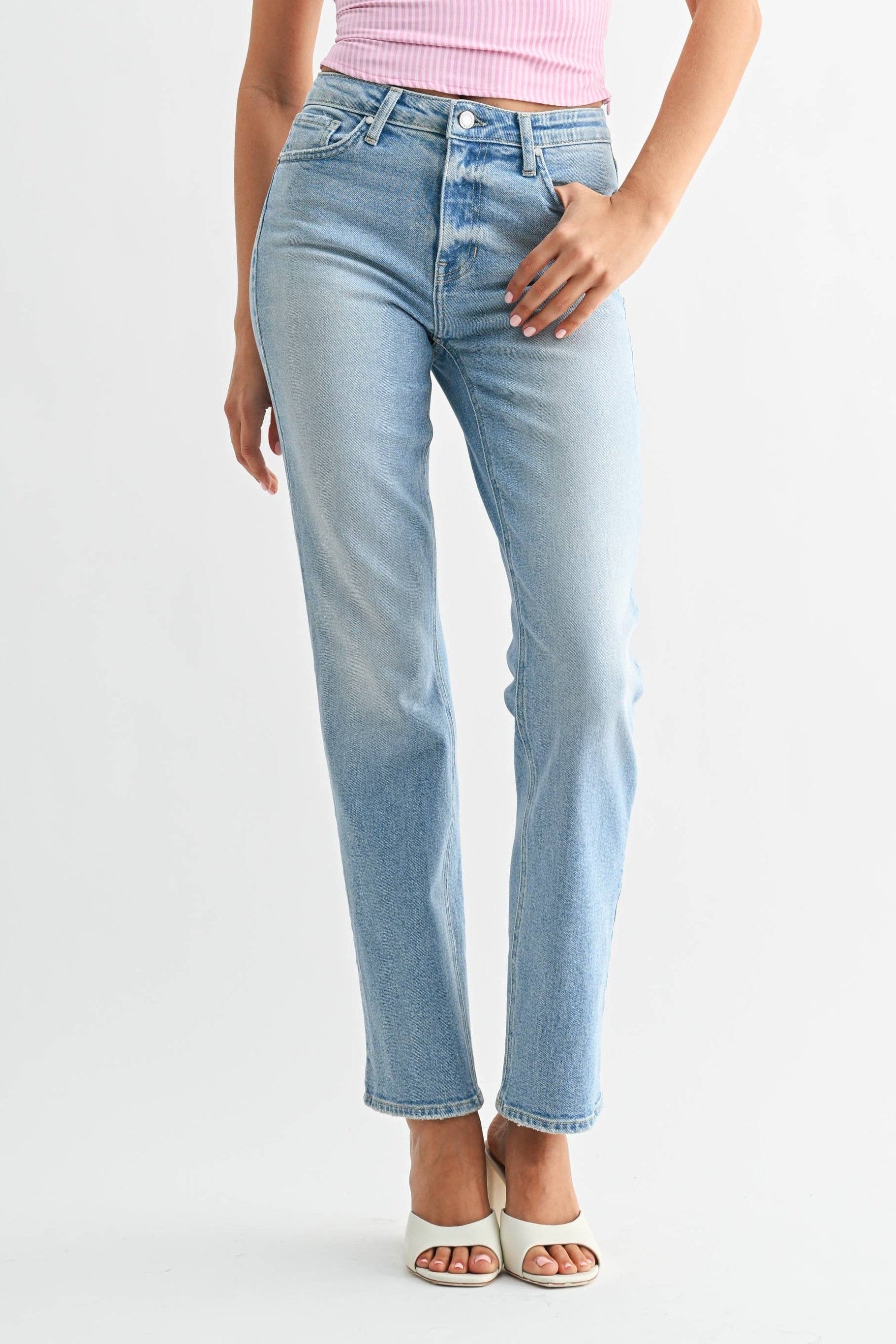 Woman wearing a pink top and light blue jeans on a white background