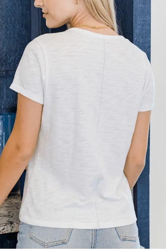Woman wearing a white t-shirt and blue jeans standing in a room with a blue wall.