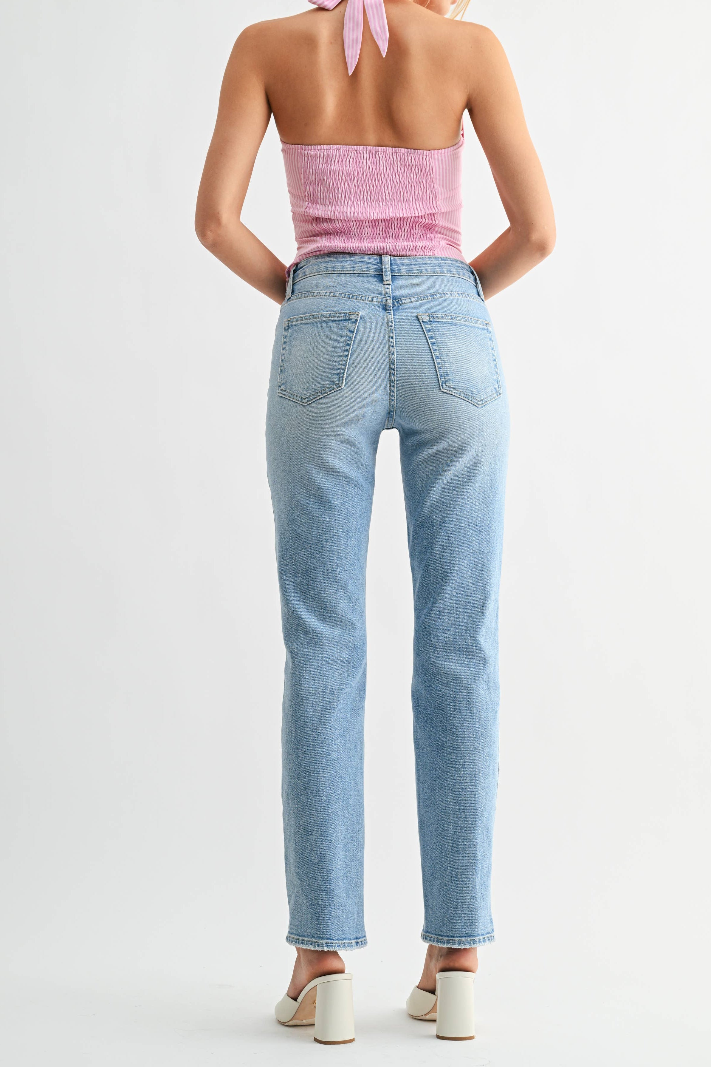 Woman wearing a pink top and light blue jeans on a white background
