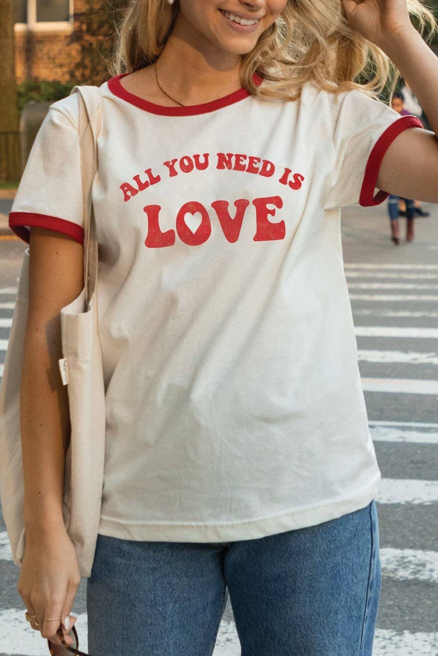 Woman wearing a 'All You Need Is Love' t-shirt on a city street.