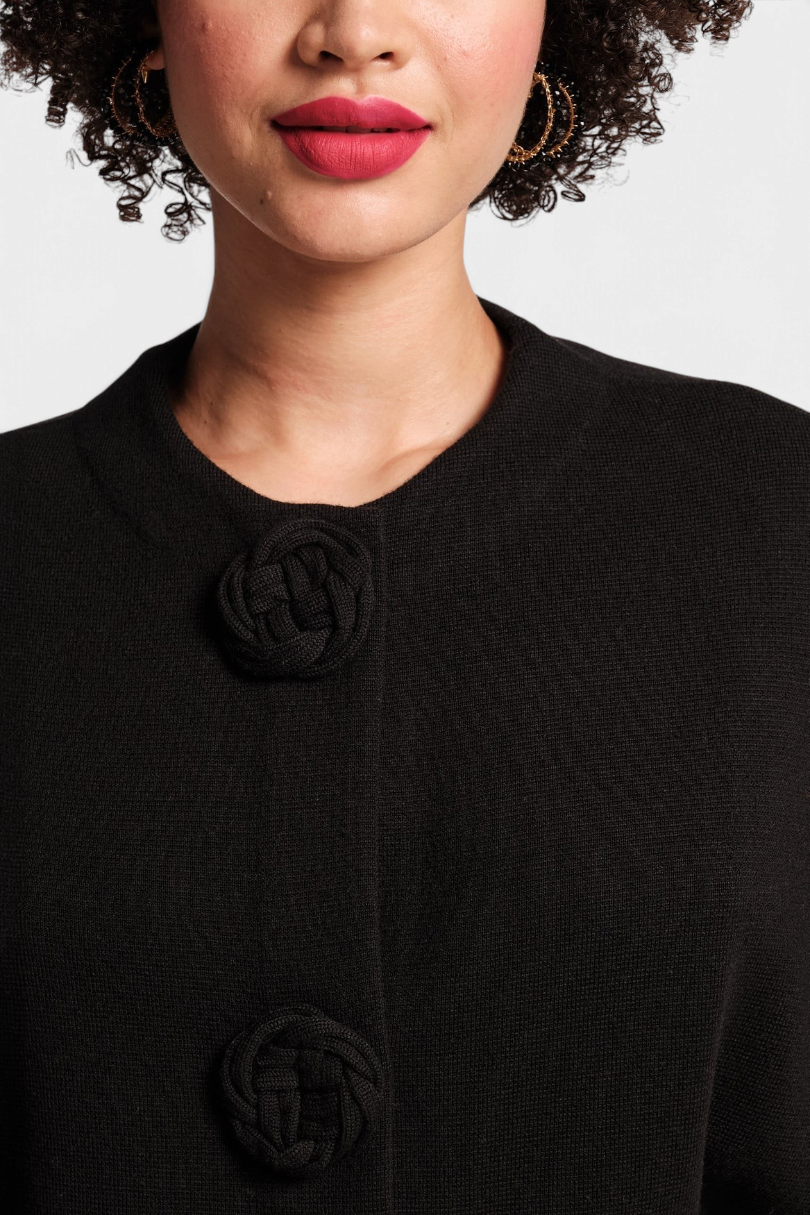 Frances Valentine Carnegie black merino wool shrug with knit rosette buttons and a scoop neckline on a model