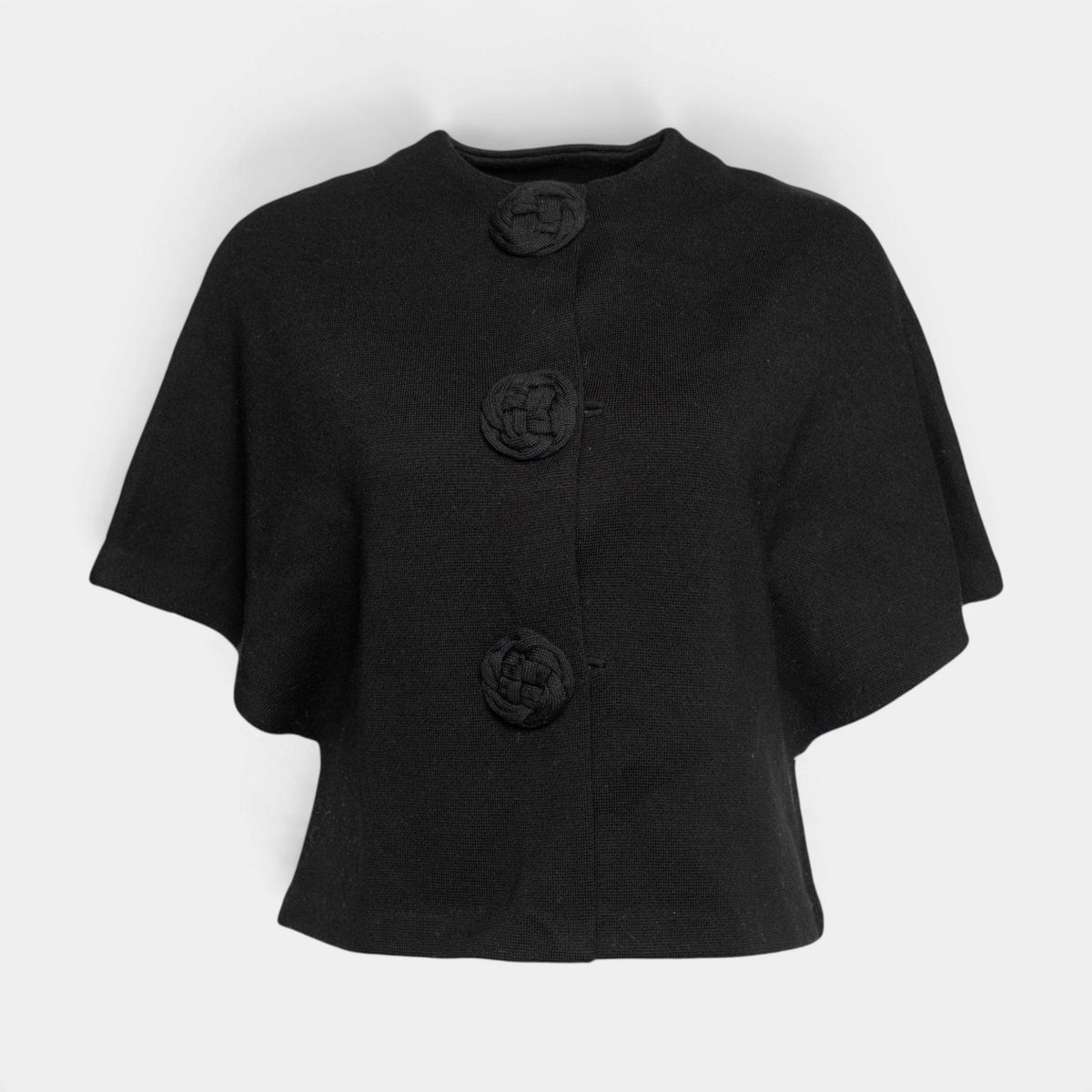 Frances Valentine black merino wool shrug with half-length batwing sleeves and three decorative floral knit buttons.