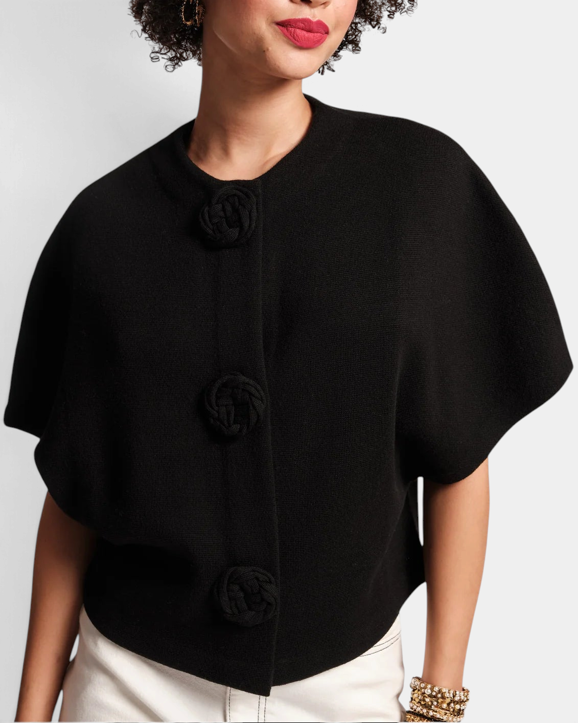 Frances Valentine Carnegie black merino wool shrug with half sleeves, scoop neck, and three floral knit buttons.
