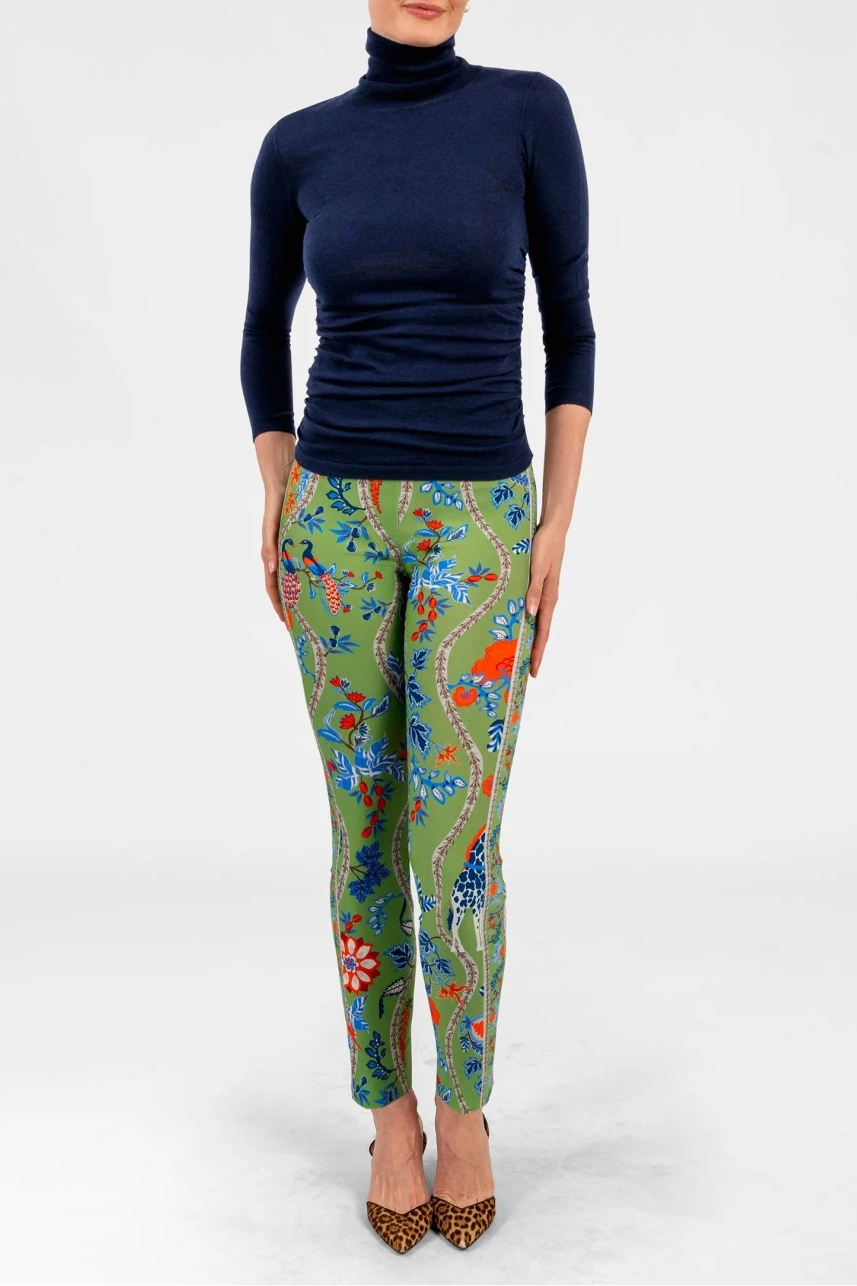 Woman wearing a navy turtleneck and colorful patterned pants on a white background