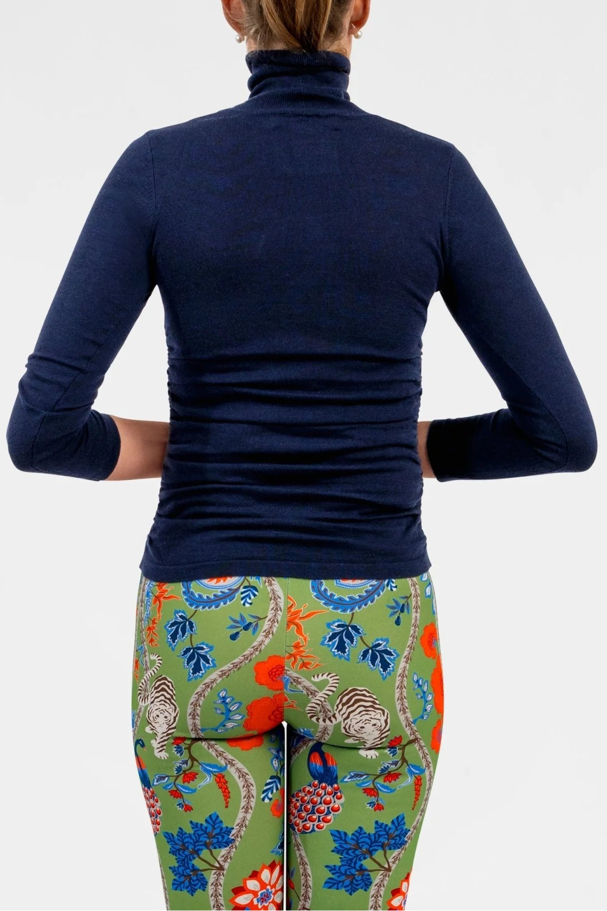 Person wearing a navy long-sleeve top and colorful patterned pants on a white background
