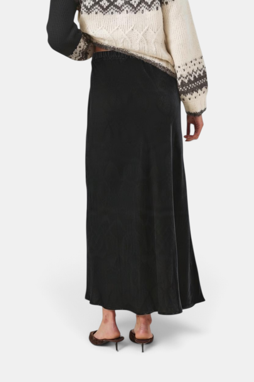 The Copper Shed black velvet maxi skirt with an A-line silhouette and elastic waist, shown from the back.