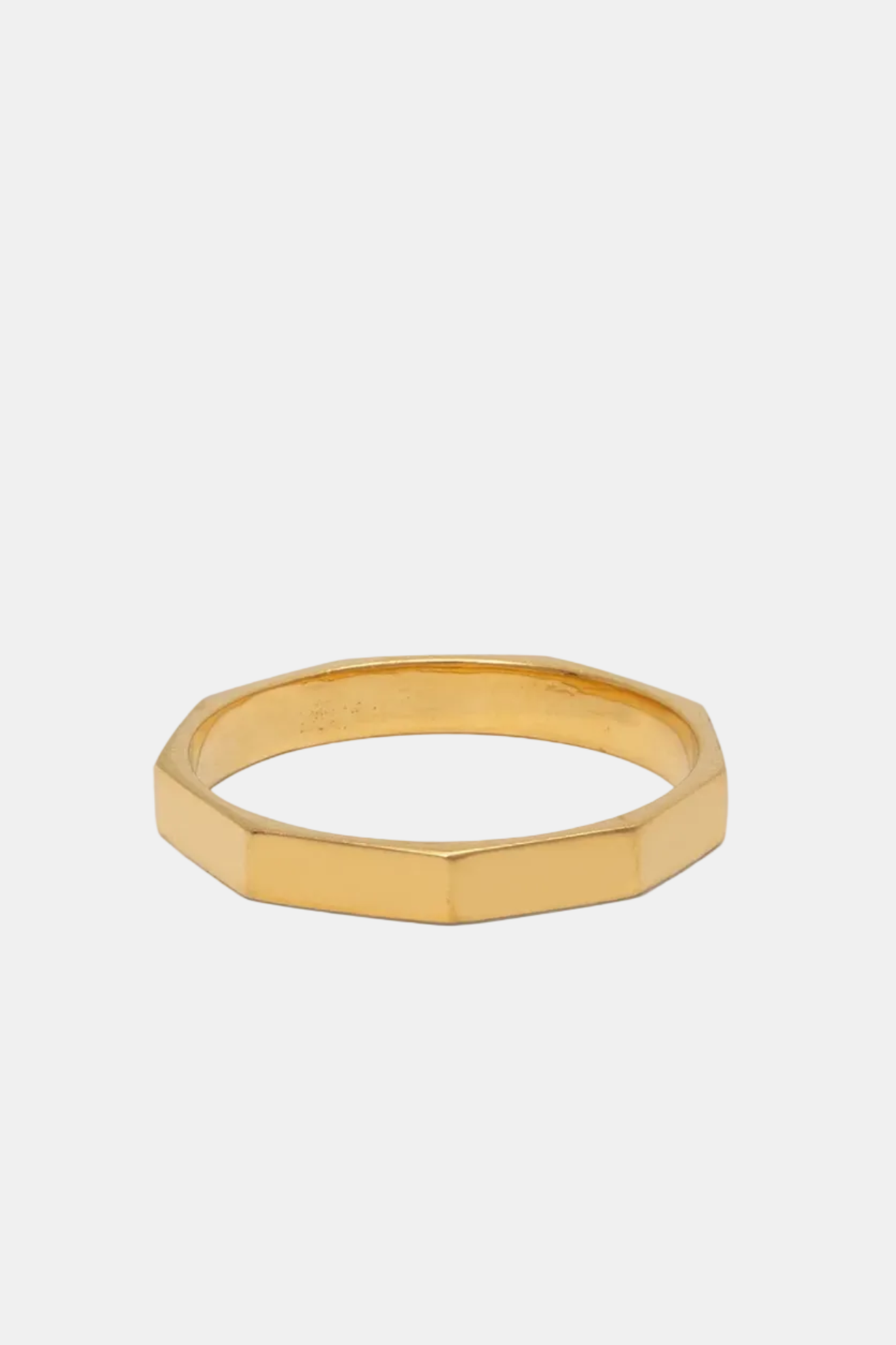 Gold ring with a geometric design on a white background