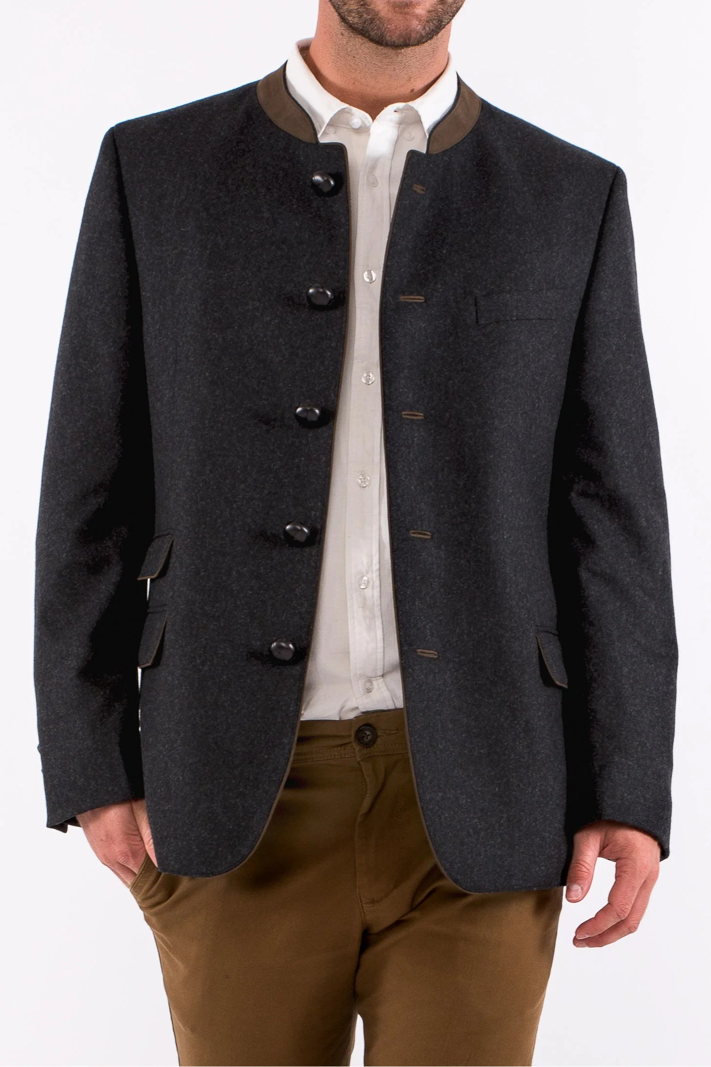 Man wearing a dark gray blazer with black buttons over a white shirt and brown pants on a white background