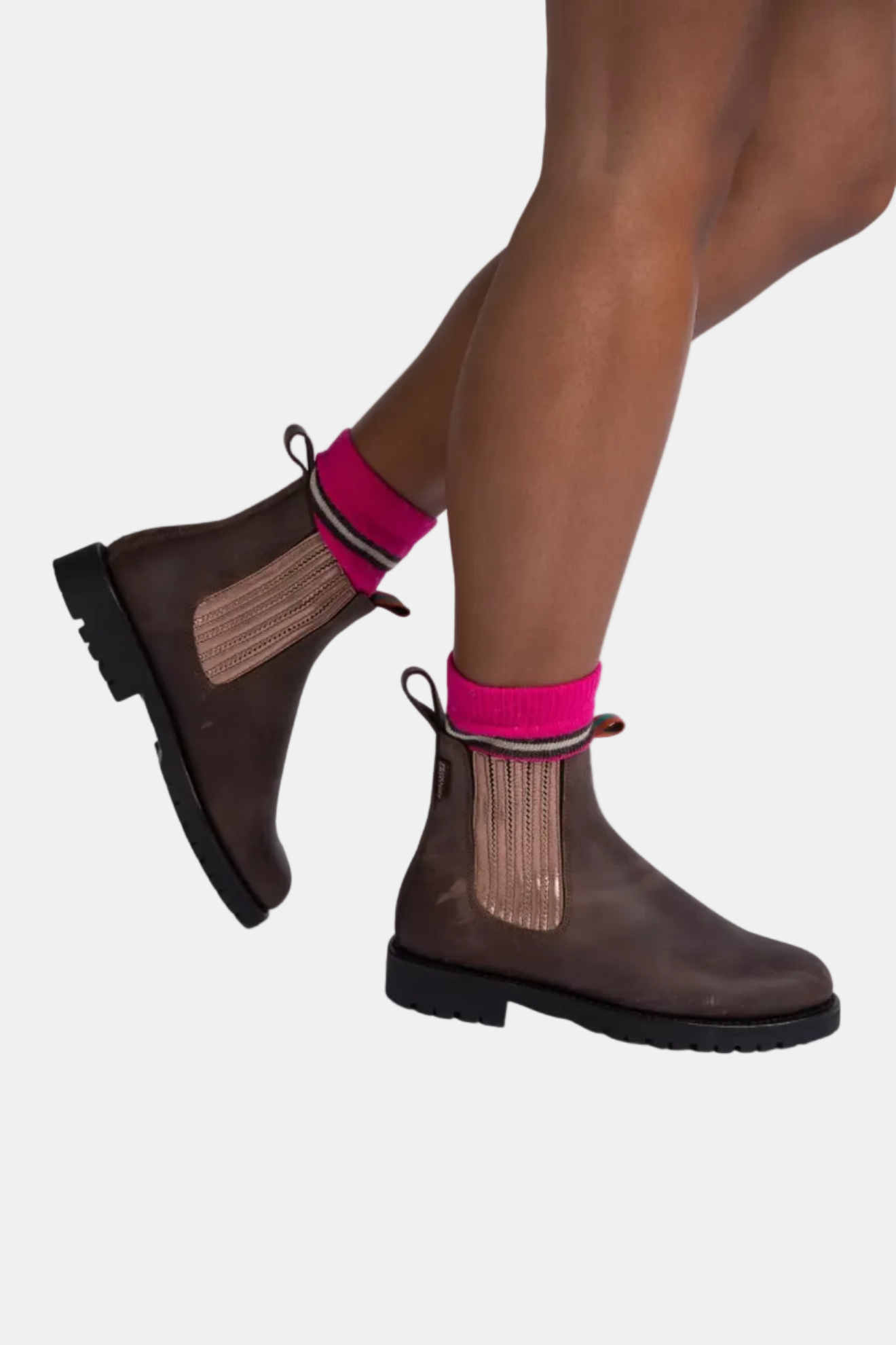 Brown boots with mesh sides worn by a person on a white background