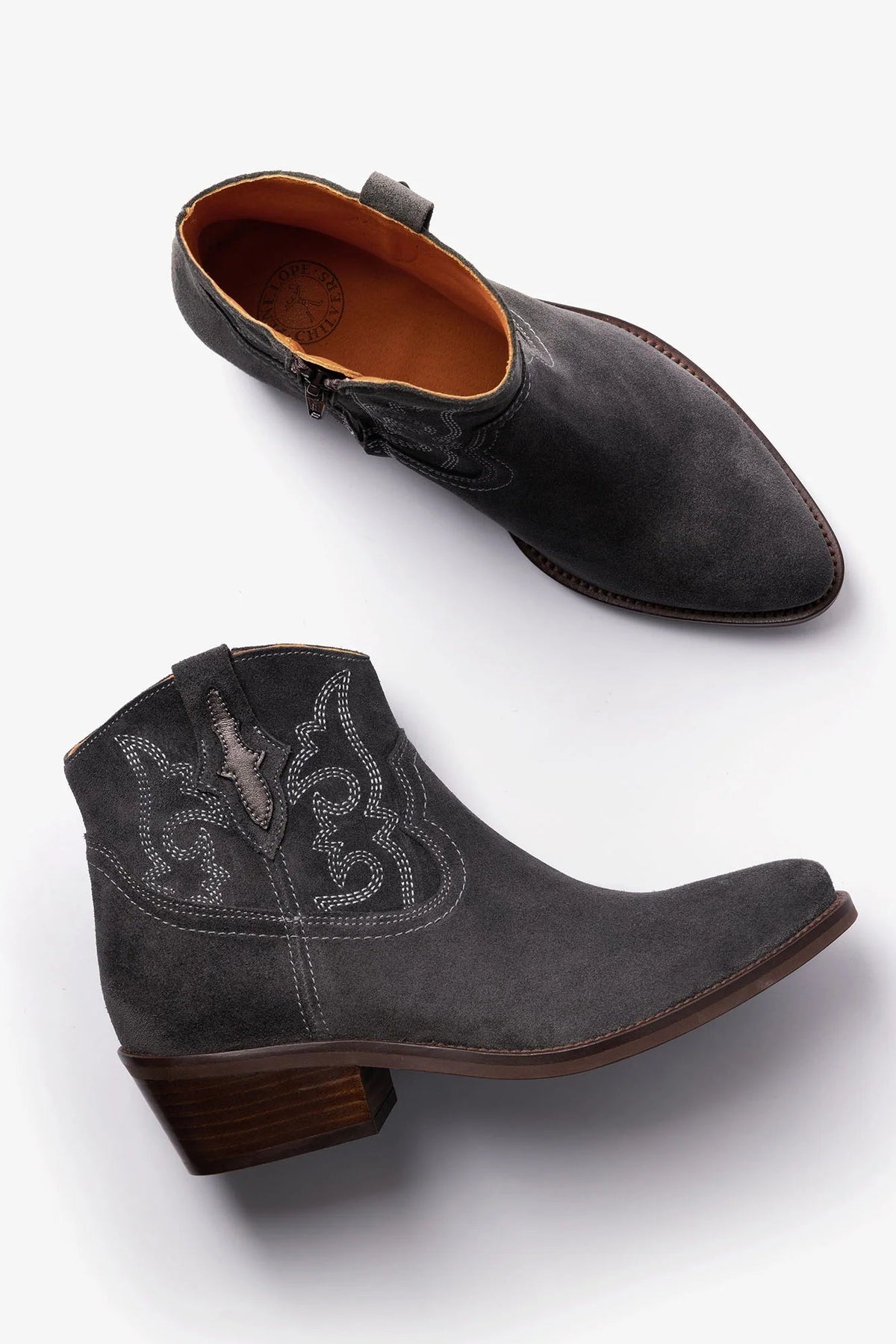 A pair of women's western ankle boots in dark charcoal gray suede, featuring pointed toes, low stacked wood-look heels, and decorative western embroidery on the side. One boot is shown from the top view and the other from the side profile, set against a clean white background.