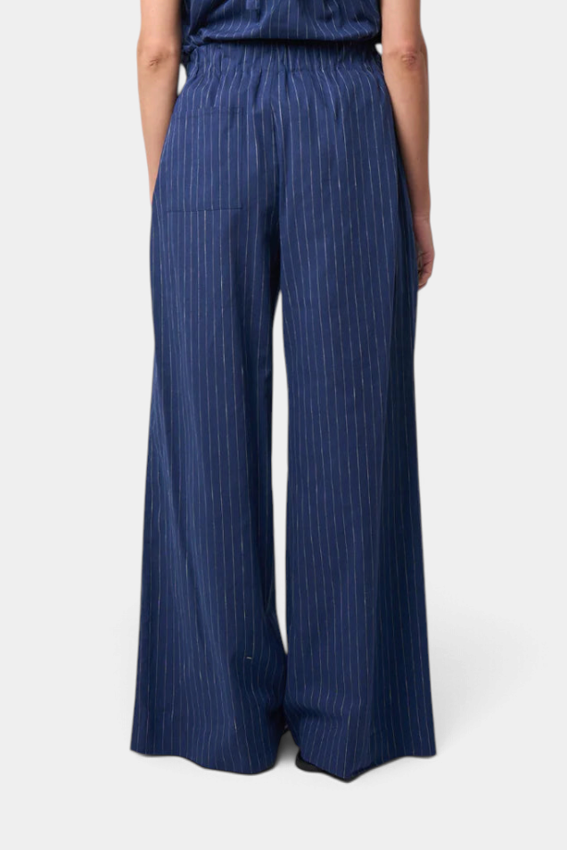 The Copper Shed Abby Pant in navy blue cotton linen with white vertical stripes and an elastic waistband, back view.
