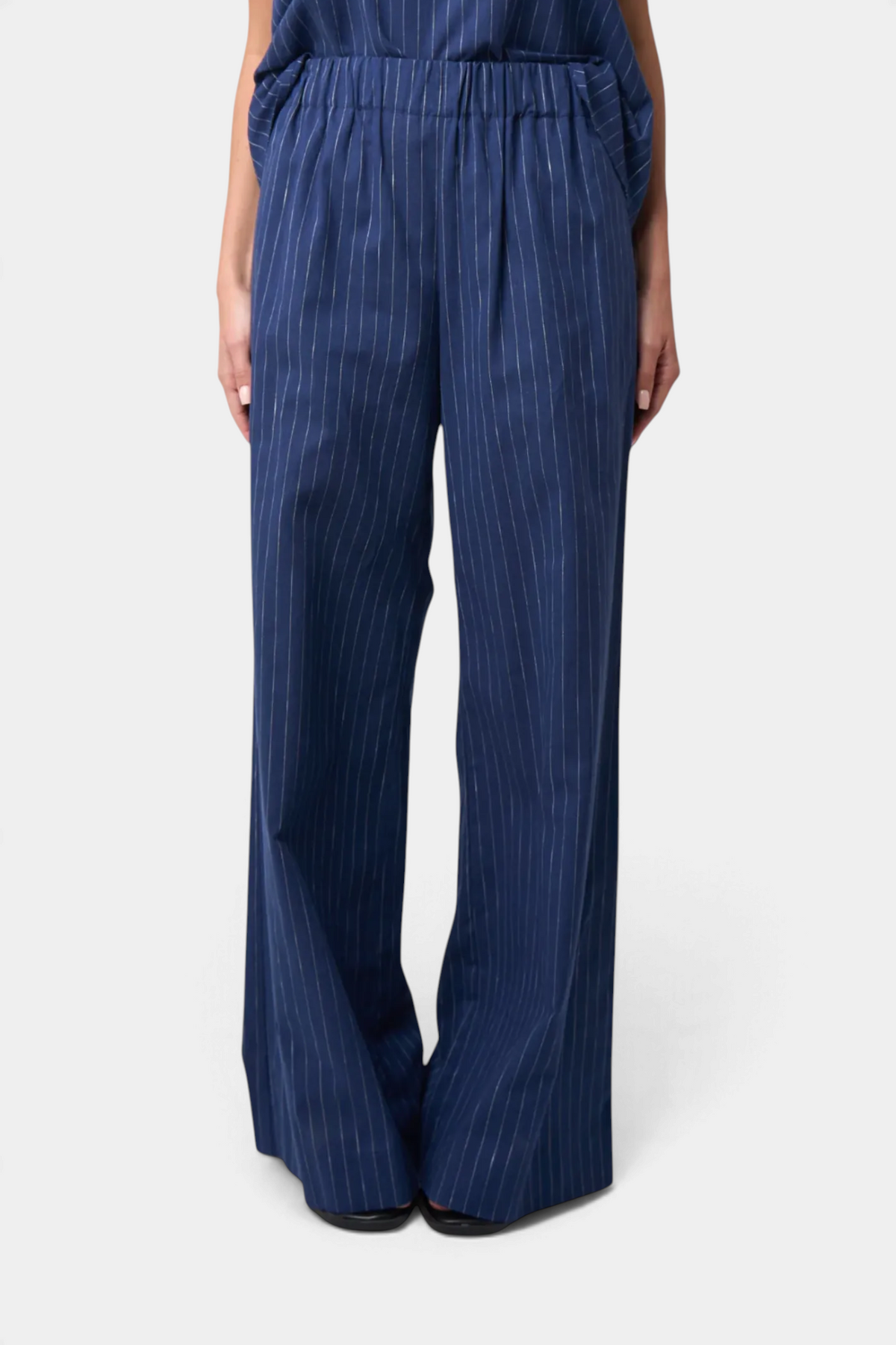 The Copper Shed Abby pant in navy blue cotton linen stripe with an elastic waistband worn by a model