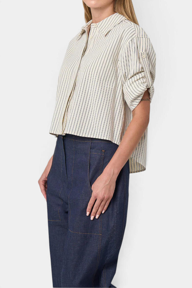 The Copper Shed Alex cropped seersucker shirt with striped pattern, roll-tab sleeves, and high-low hem on a model.