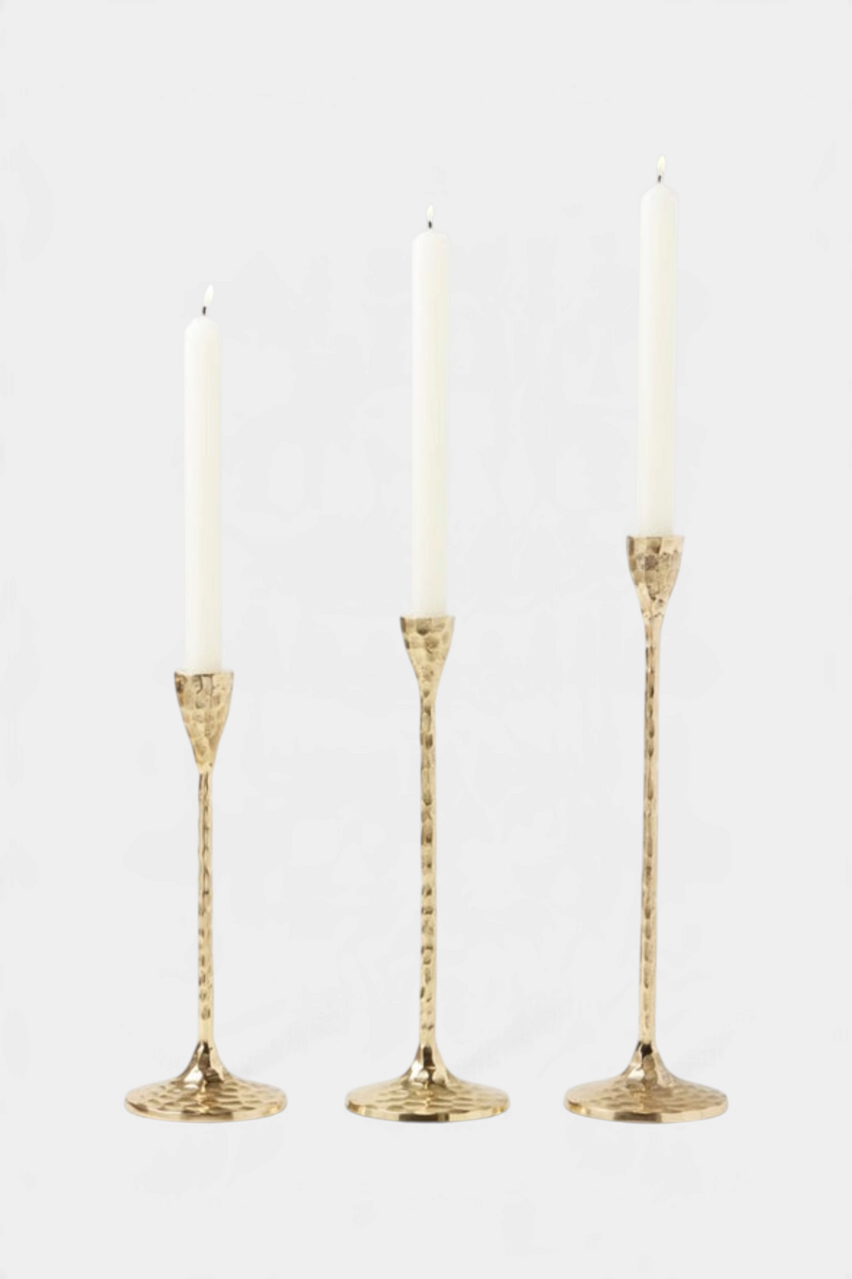 The Copper Shed set of three gold hammered brass candlestick holders with slender silhouettes and white taper candles