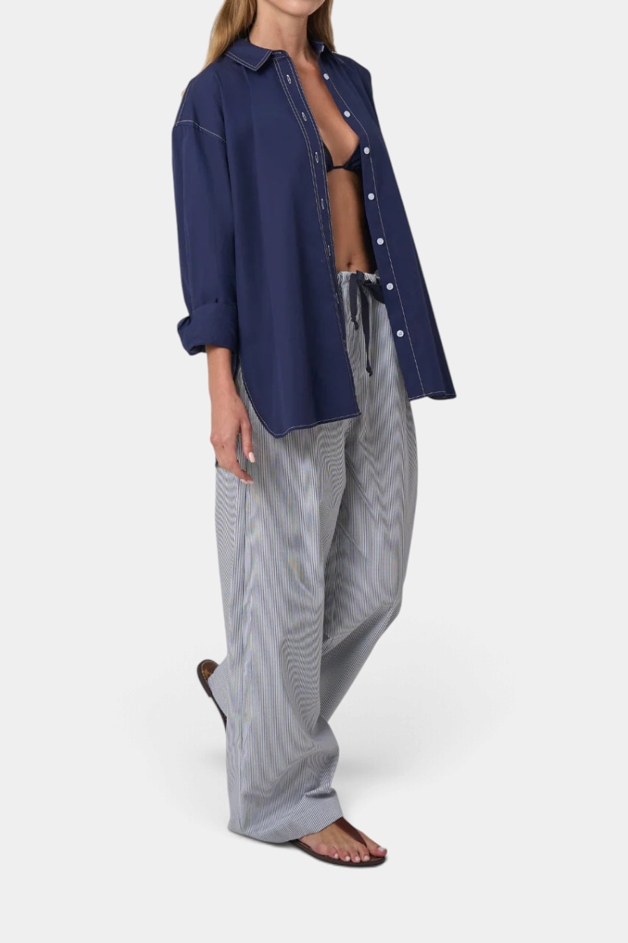 Model wearing The Copper Shed Alyssa drawstring cotton pants in a grey striped pattern with a navy button-down shirt.