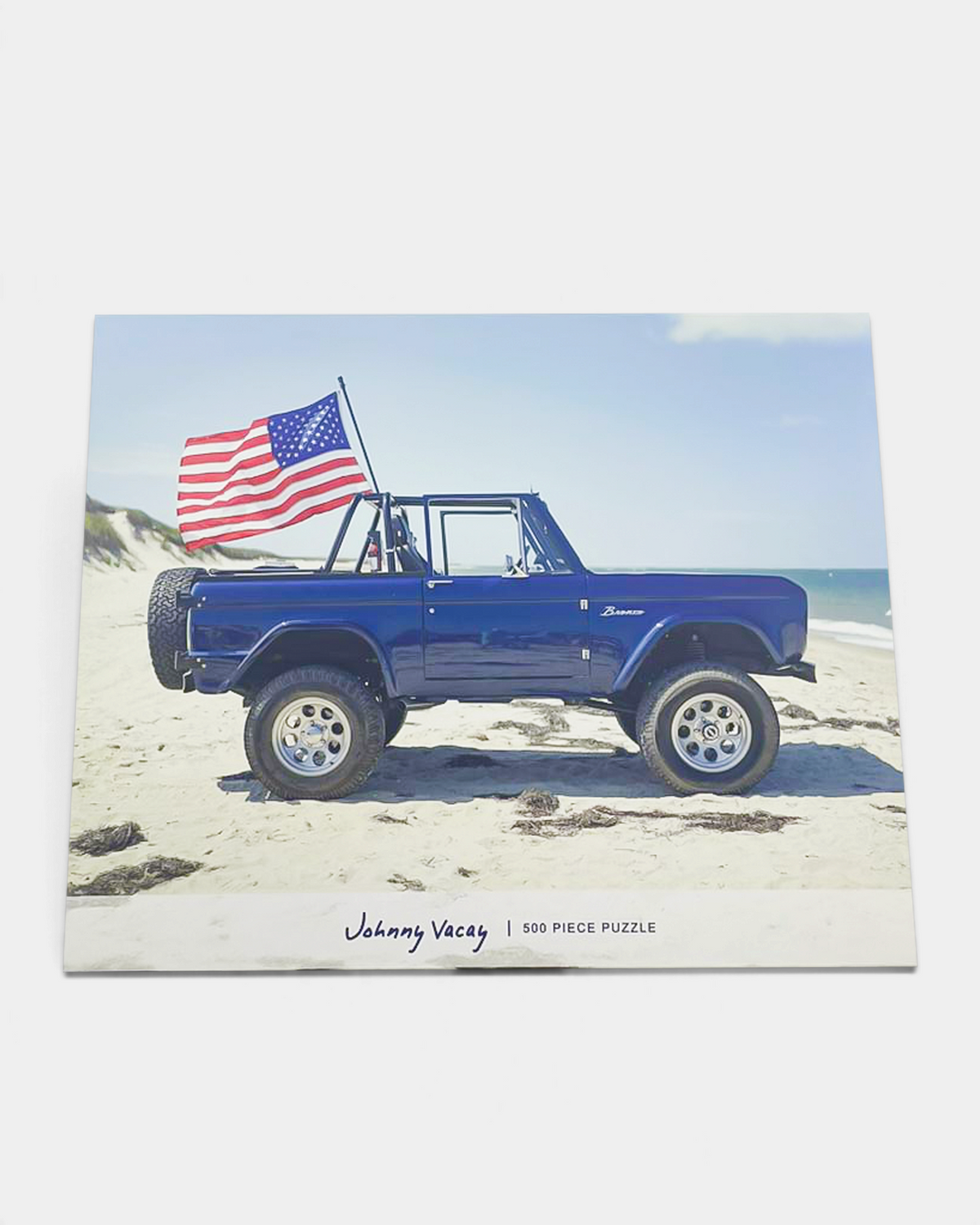 The Copper Shed American Bronco 500 piece puzzle featuring a blue vintage Ford Bronco with an American flag on a beach