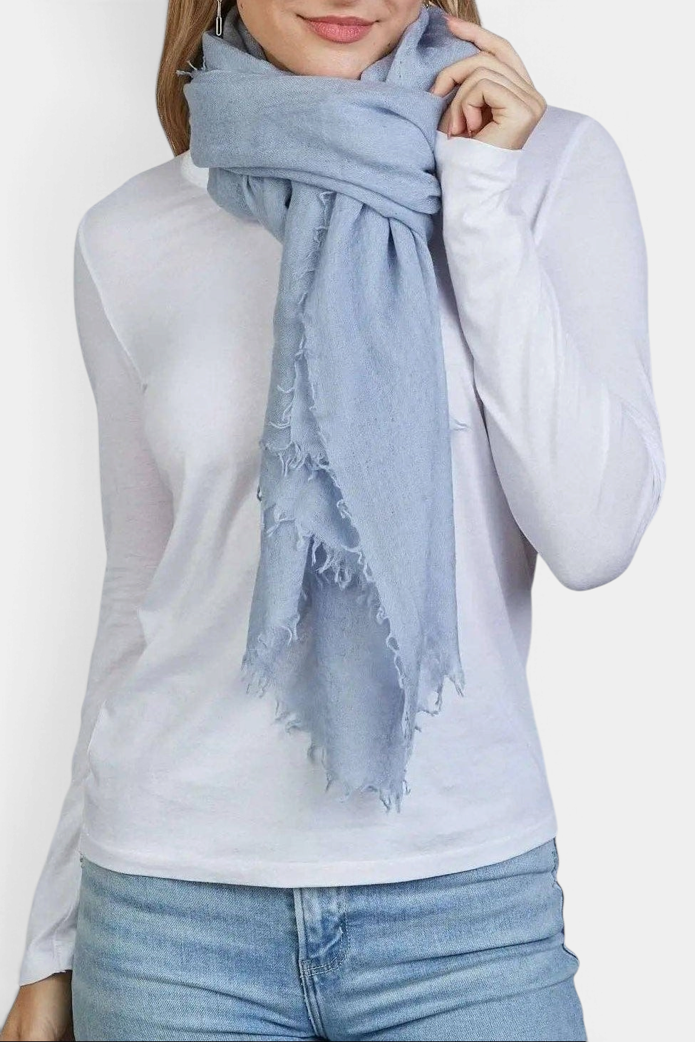 The Copper Shed arctic blue 100% Mongolian cashmere scarf with frayed edges worn by a woman in a white long-sleeve top.