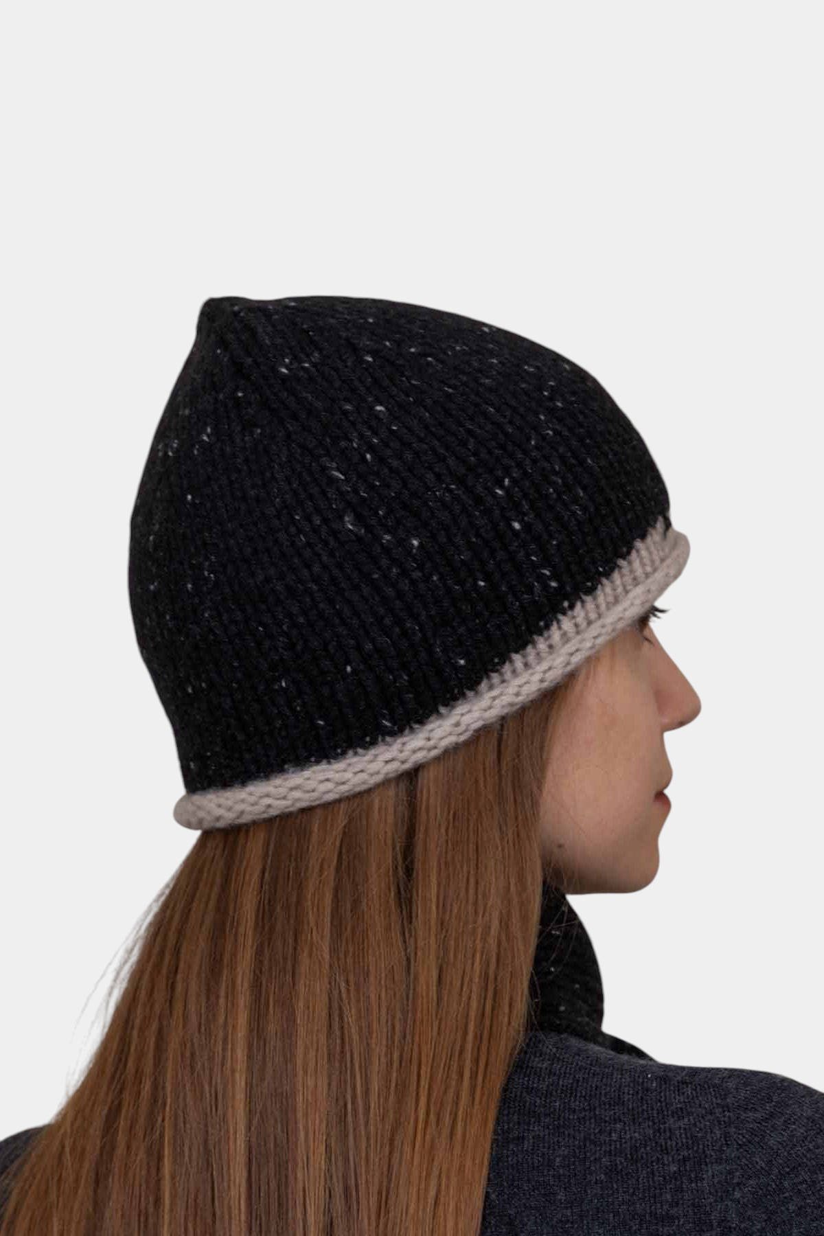 The Copper Shed hand-knitted black organic cashmere beanie with a contrasting beige rolled edge on a model