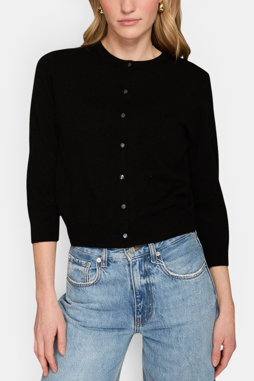 The Copper Shed black cashmere crew neck cardigan with front button closure worn by a model with blue jeans.