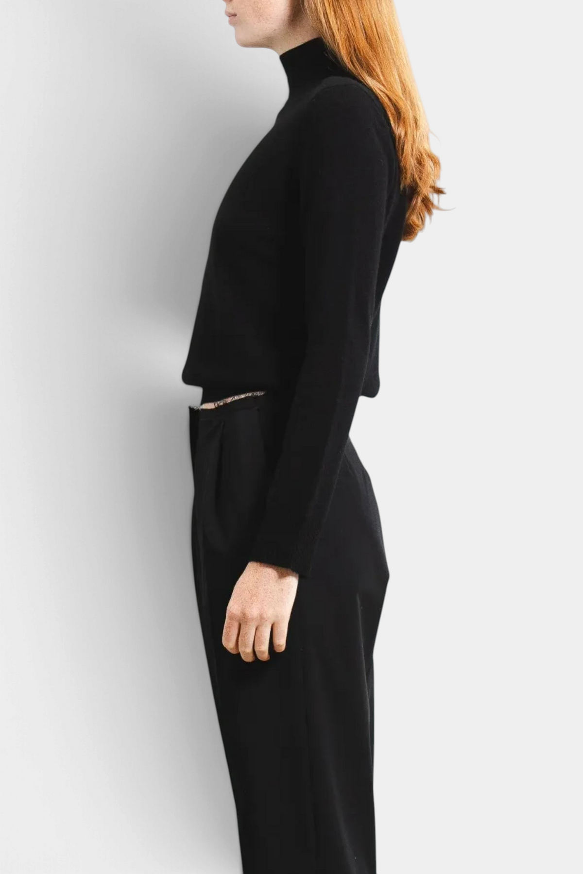 The Copper Shed black cashmere high neck long sleeve sweater worn by a woman in a side profile view.