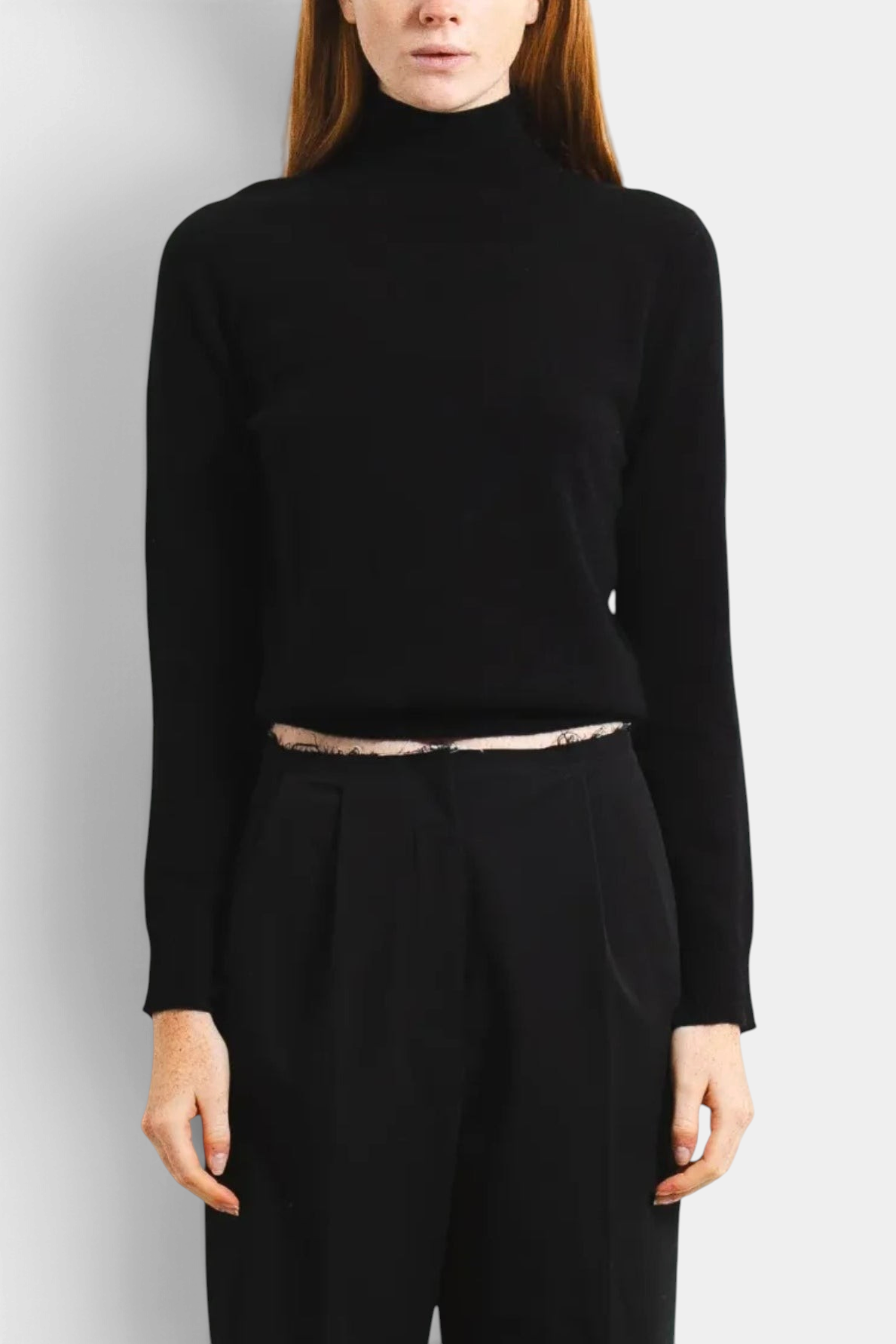 The Copper Shed black cashmere high neck long sleeve sweater worn by a model with red hair against a white background.