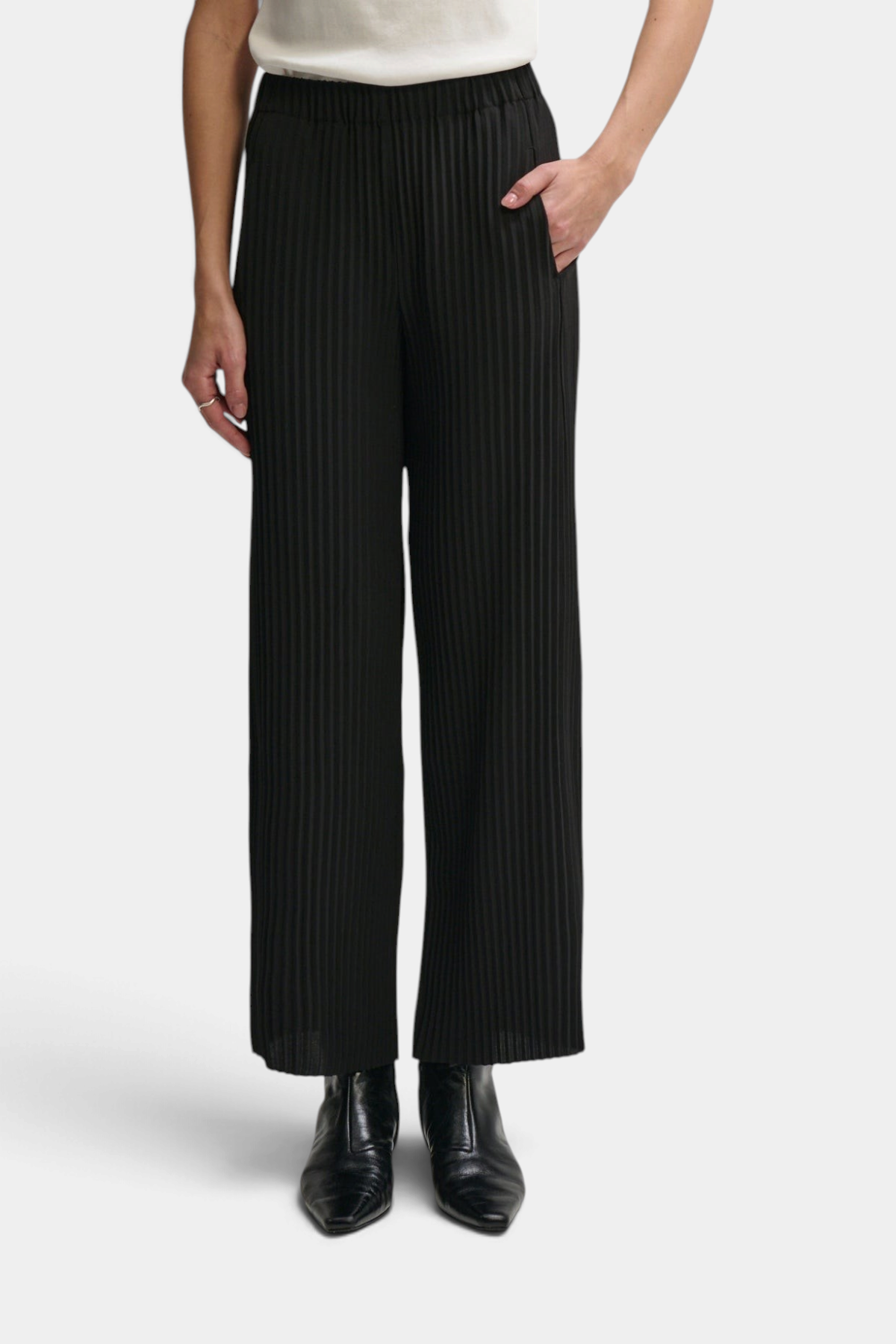 The Copper Shed high-rise black pleated pull-on pants with an elastic waistband and side pockets on a model