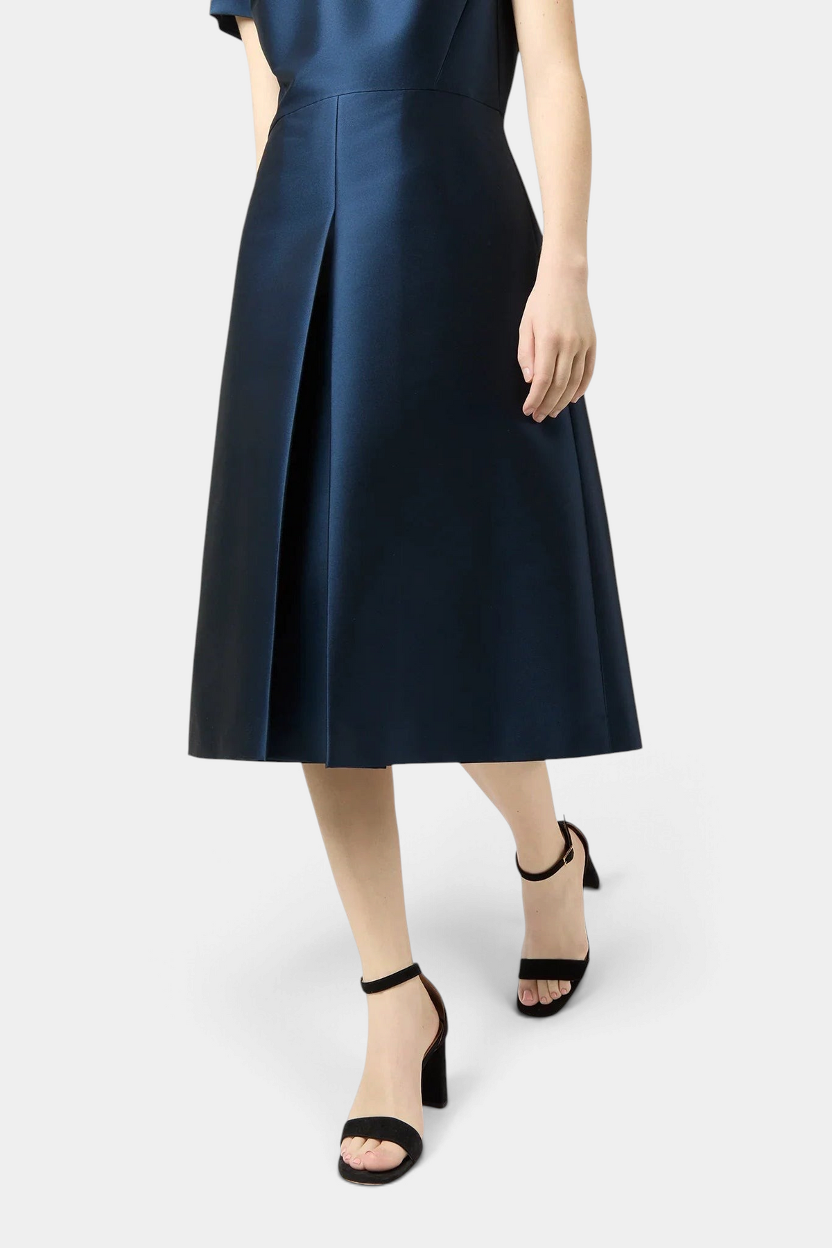 The Copper Shed black suede ankle-wrap block heel sandals worn with a navy blue satin midi skirt