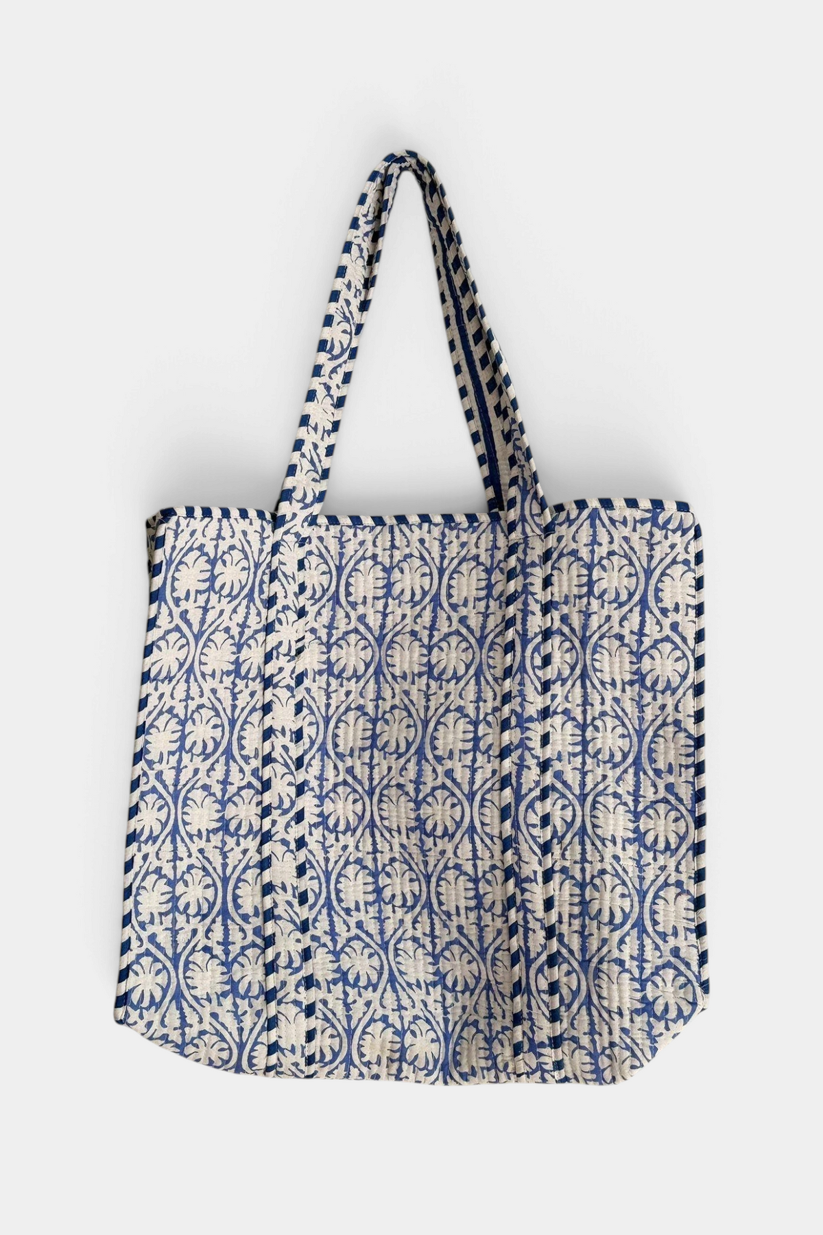 The Copper Shed reversible quilted cotton tote bag with blue and white floral block print and striped handles.