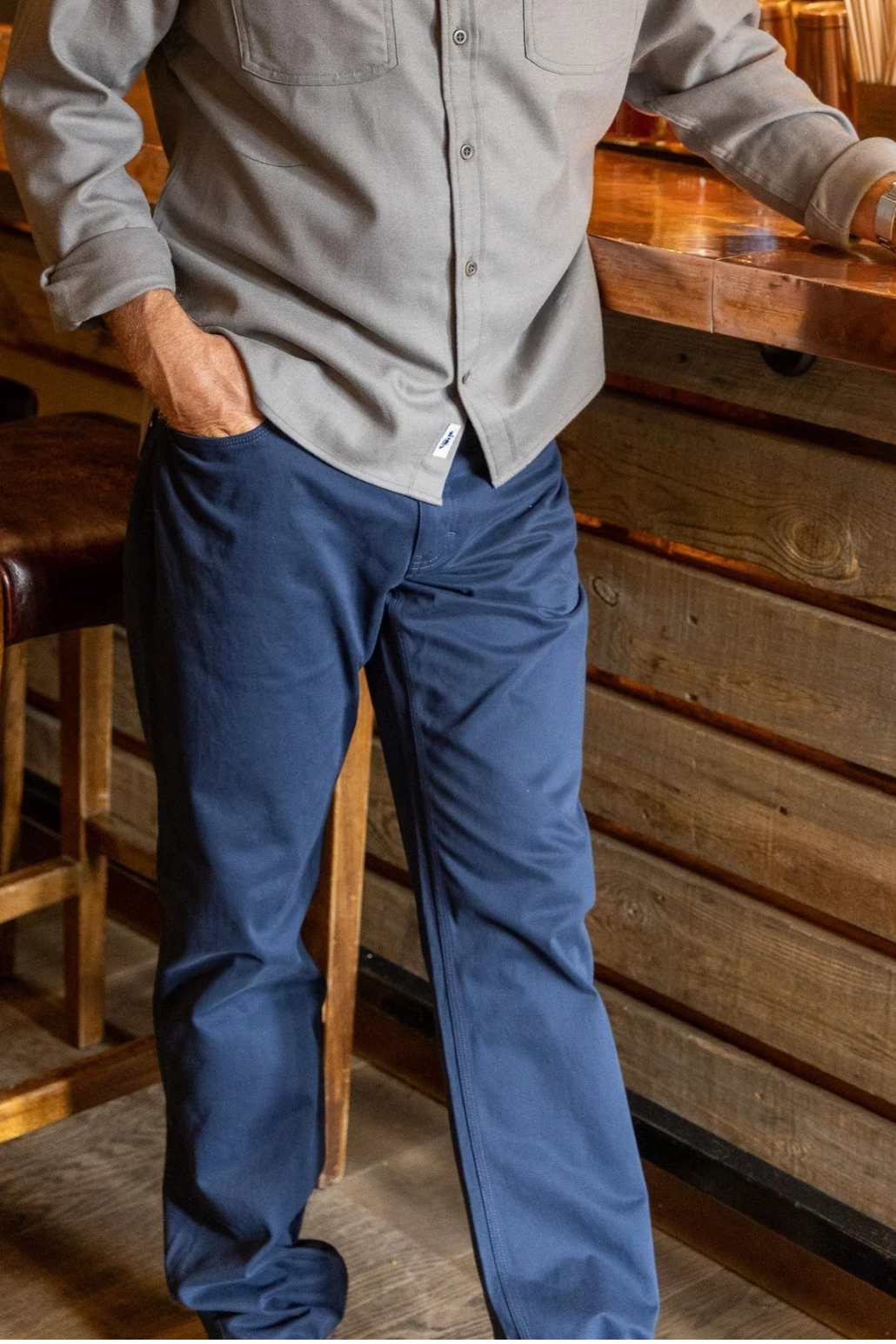 A man wearing The Copper Shed Breakout navy blue broken twill pants with 5-pocket styling in a bar setting.