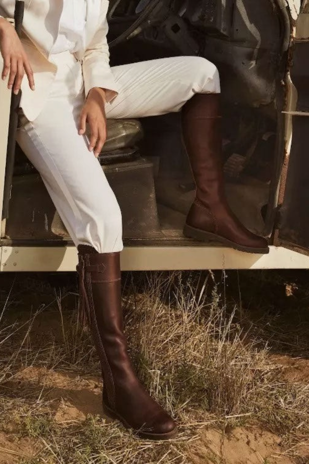 The Copper Shed brown leather tassel boots with Goodyear welted rubber soles worn by a woman in white trousers.