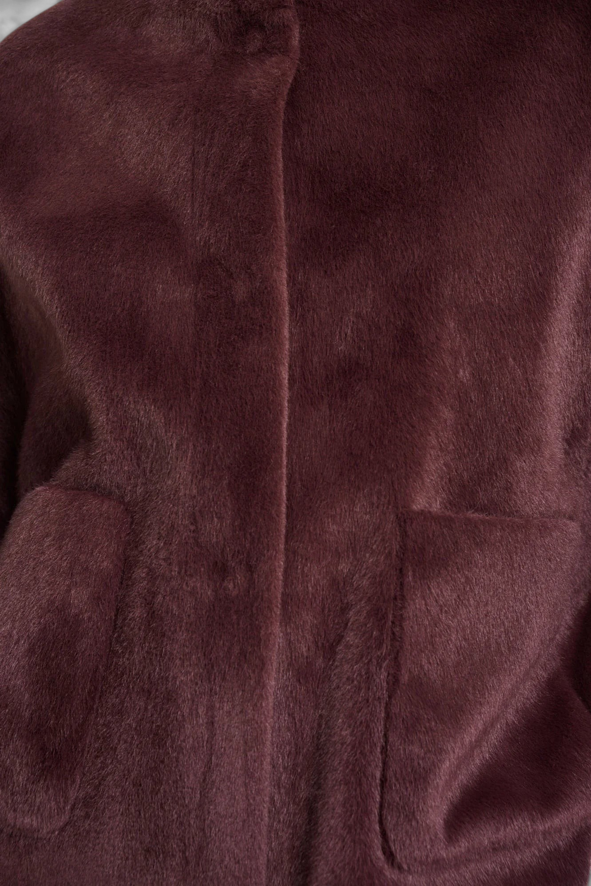 Close-up of The Copper Shed Dewi cape in deep burgundy faux fur with a front button placket and patch pockets.