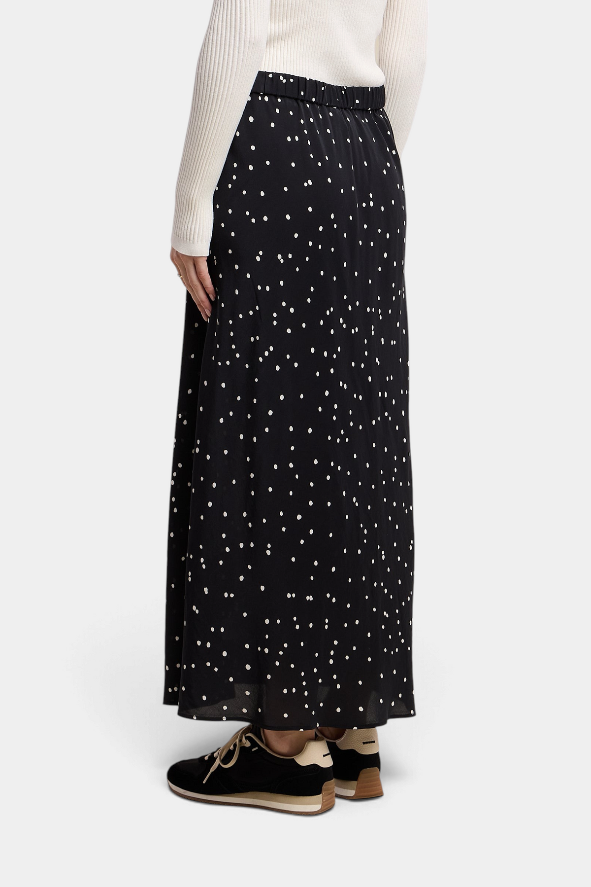 The Copper Shed Cadence black silk maxi skirt with white polka dots, featuring an A-line silhouette and elastic waist.