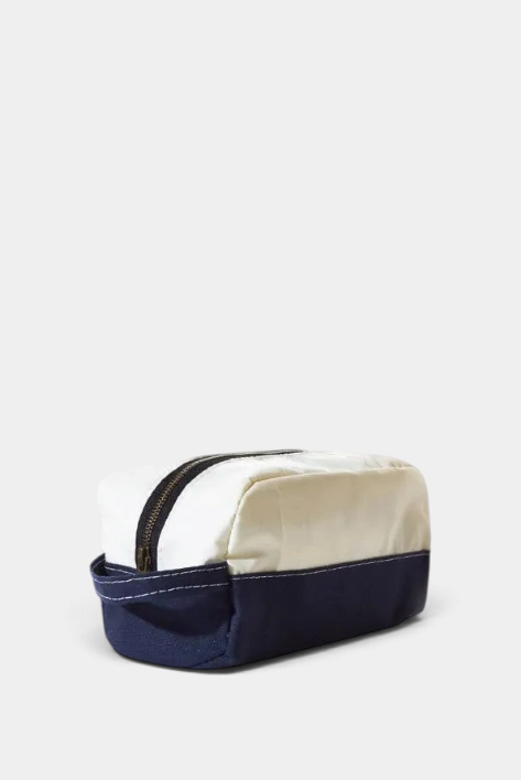 The Copper Shed Chebeague toiletry bag in white Dacron sailcloth with a navy canvas bottom and antique brass zipper.