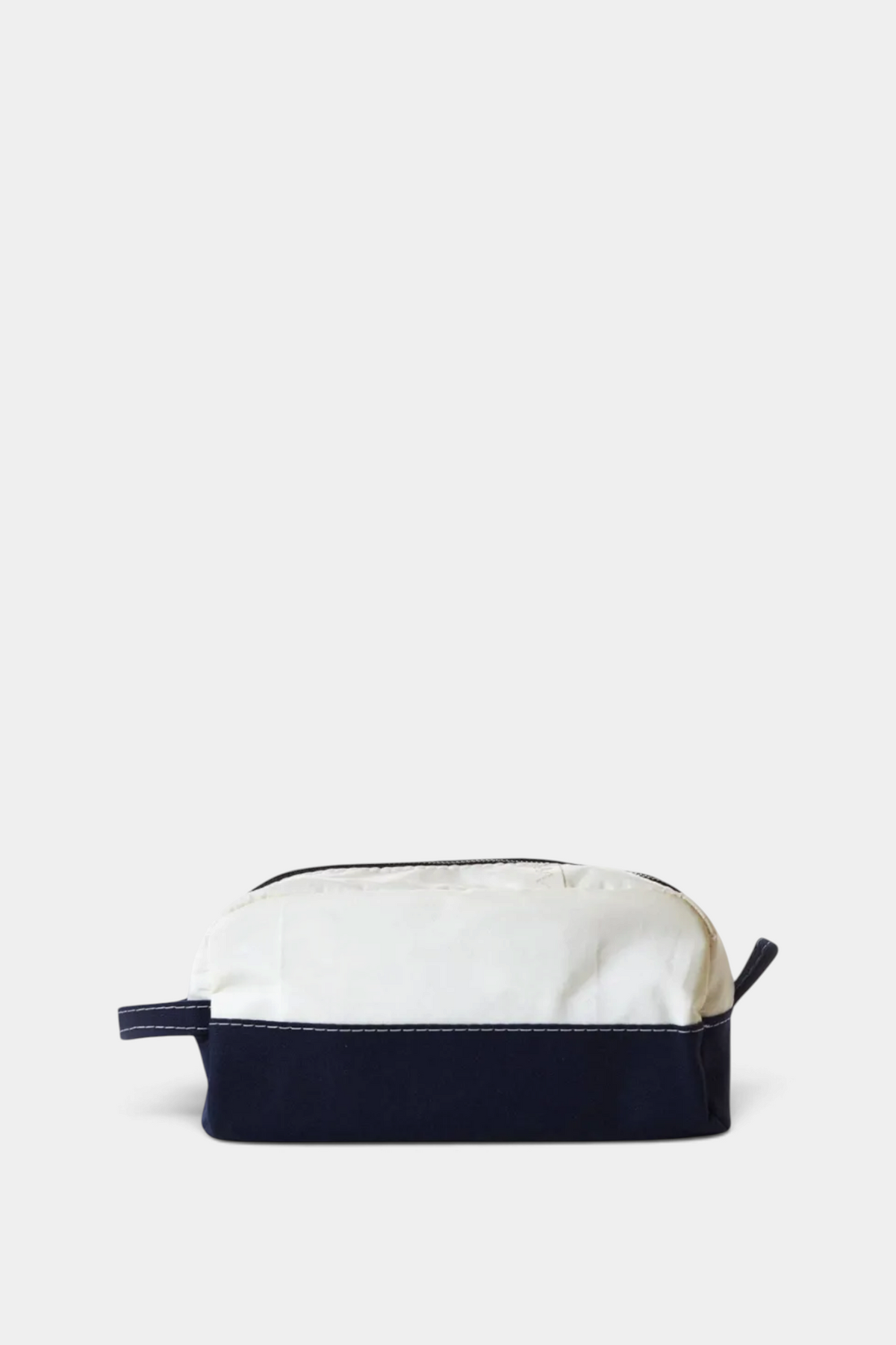 The Copper Shed Chebeague toiletry bag in white Dacron sailcloth with a navy canvas base and antique brass zipper.