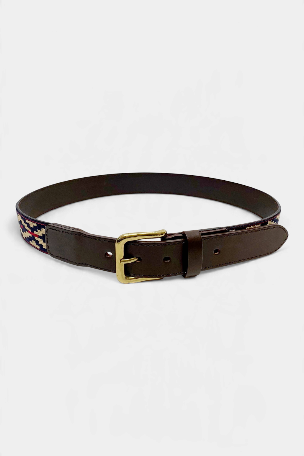 The Copper Shed Cinta Pampa polo belt in brown vegetable tanned leather with a navy, tan, and red woven cotton pattern.