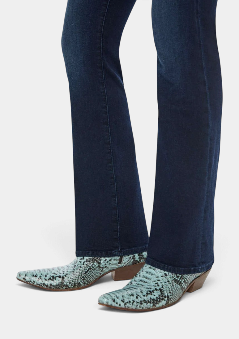 The Copper Shed mid-rise flared dark blue stretch denim jeans with a clean hem worn with light blue snakeskin boots.